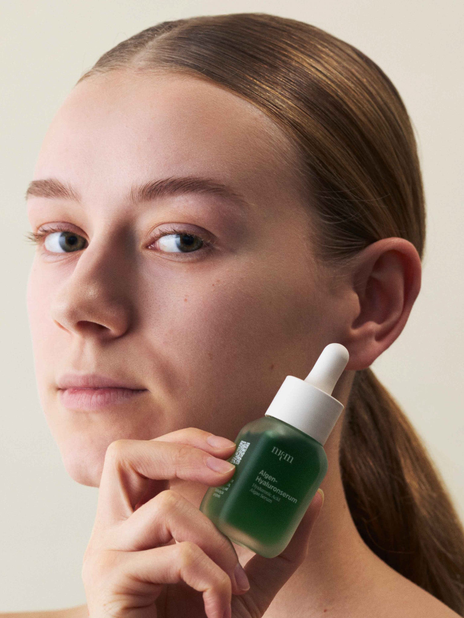 Eine Frau, die das Algen-Hyaluronserum der Hand hält