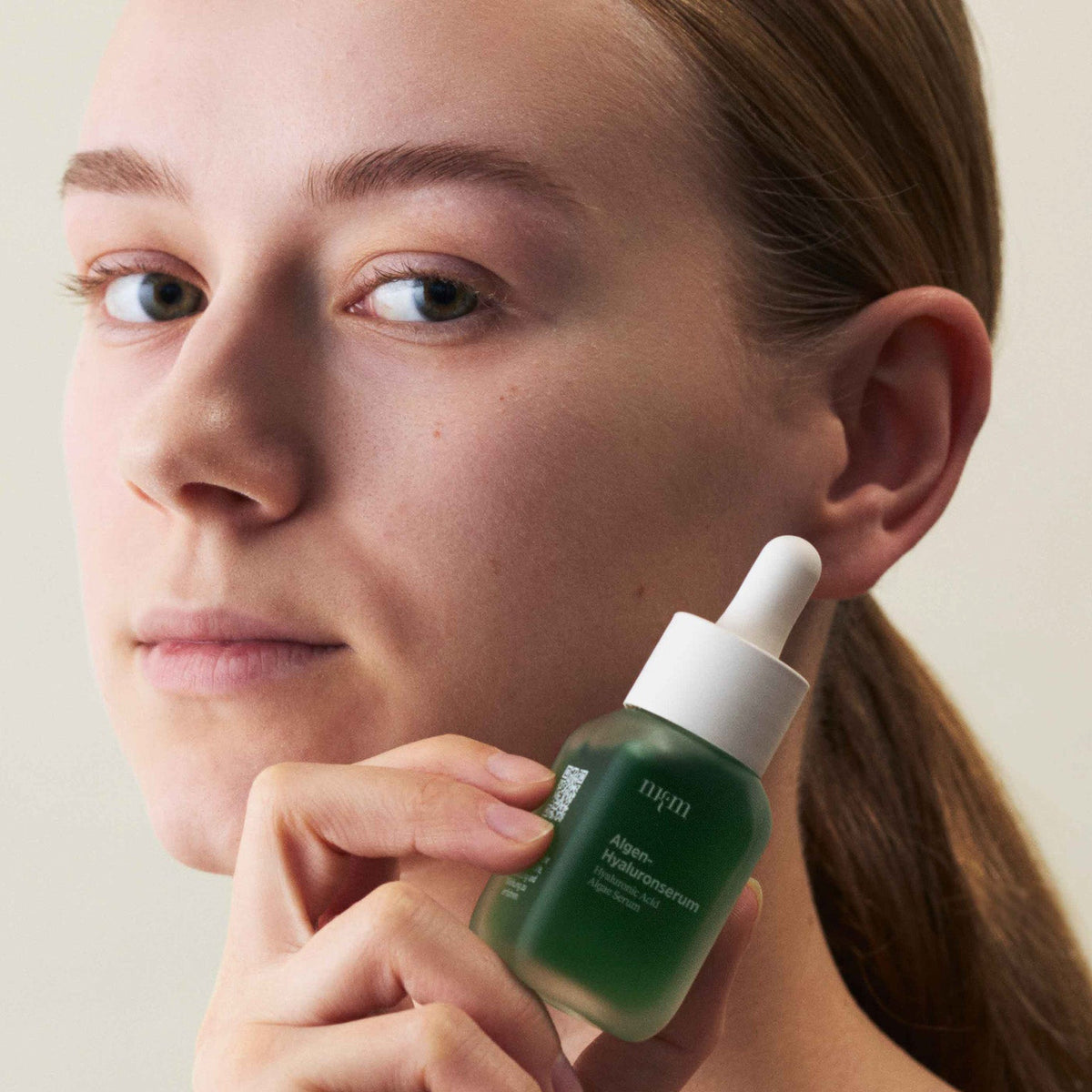 Eine Frau, die das Algen-Hyaluronserum der Hand hält