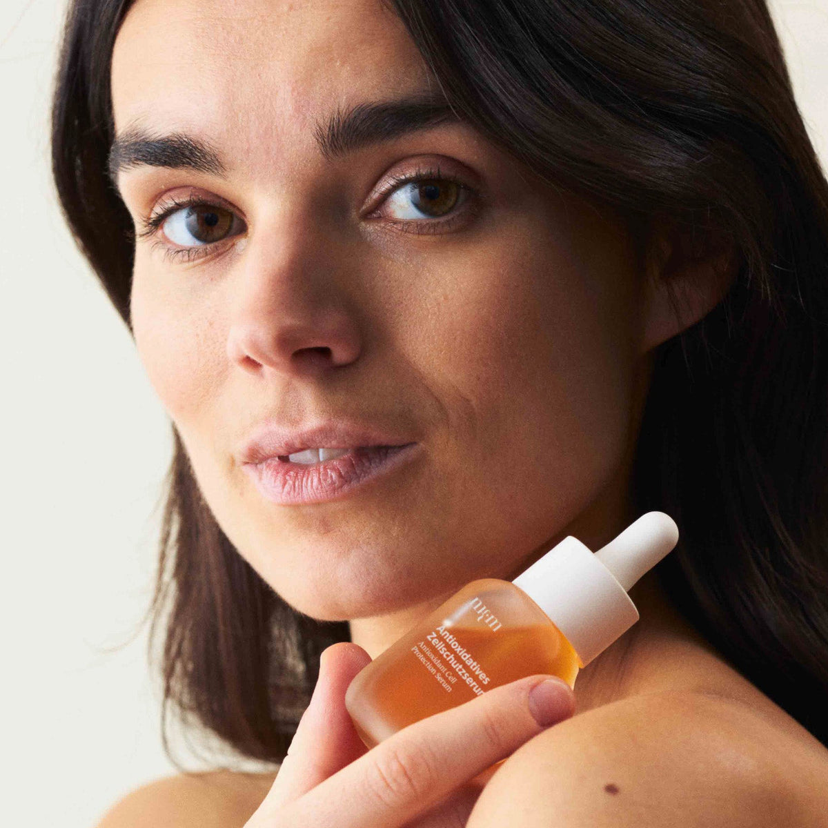 Eine Frau, die das Antioxidative Zellschutzserum in der Hand hält