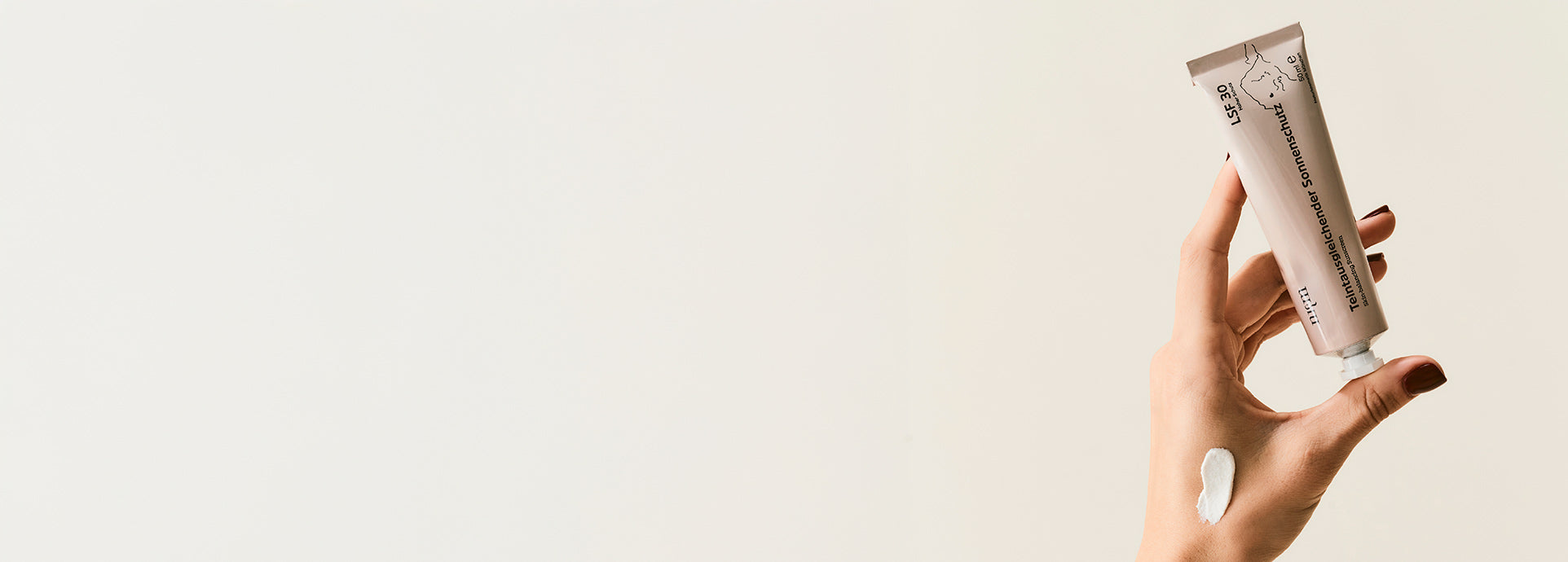 Hand hält Teintausgleichenden Sonnenschutz