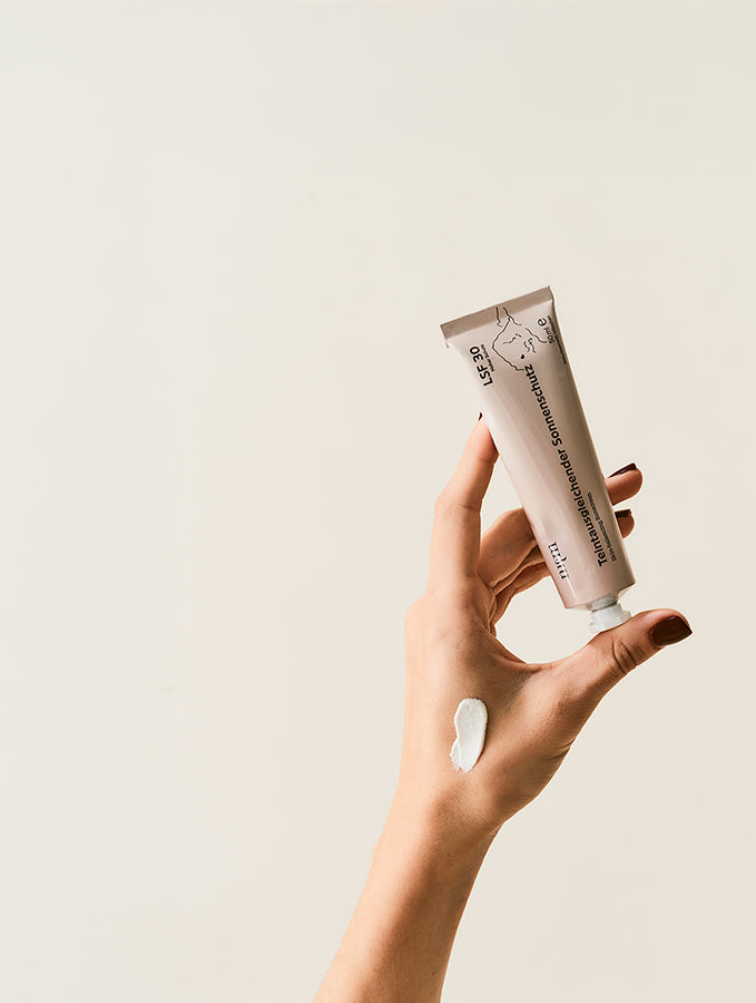 Hand hält Teintausgleichenden Sonnenschutz