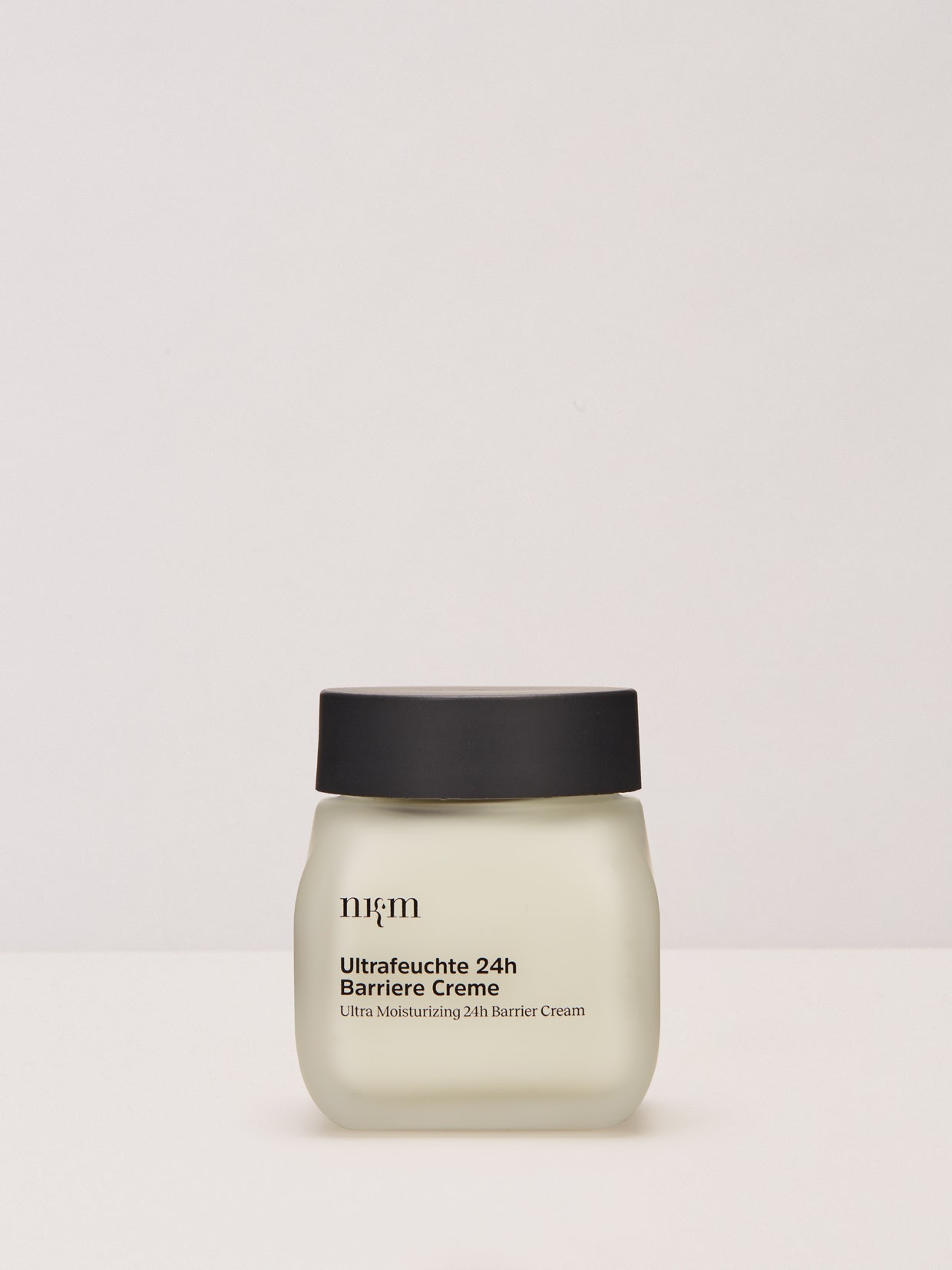 Ein Tiegel der nkm Naturkosmetik München GmbH Ultrafeuchte 24h Barriere Creme mit schwarzem Deckel steht vor einem schlichten, hellen Hintergrund.