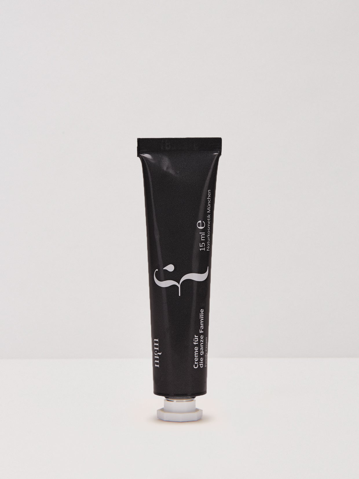 Auf weißer Fläche und Hintergrund steht eine schwarze Tube der "Reisegröße Creme für die ganze Familie" der nkm Naturkosmetik München GmbH, ideal für die intensive Pflege der empfindlichen Haut für die ganze Familie.