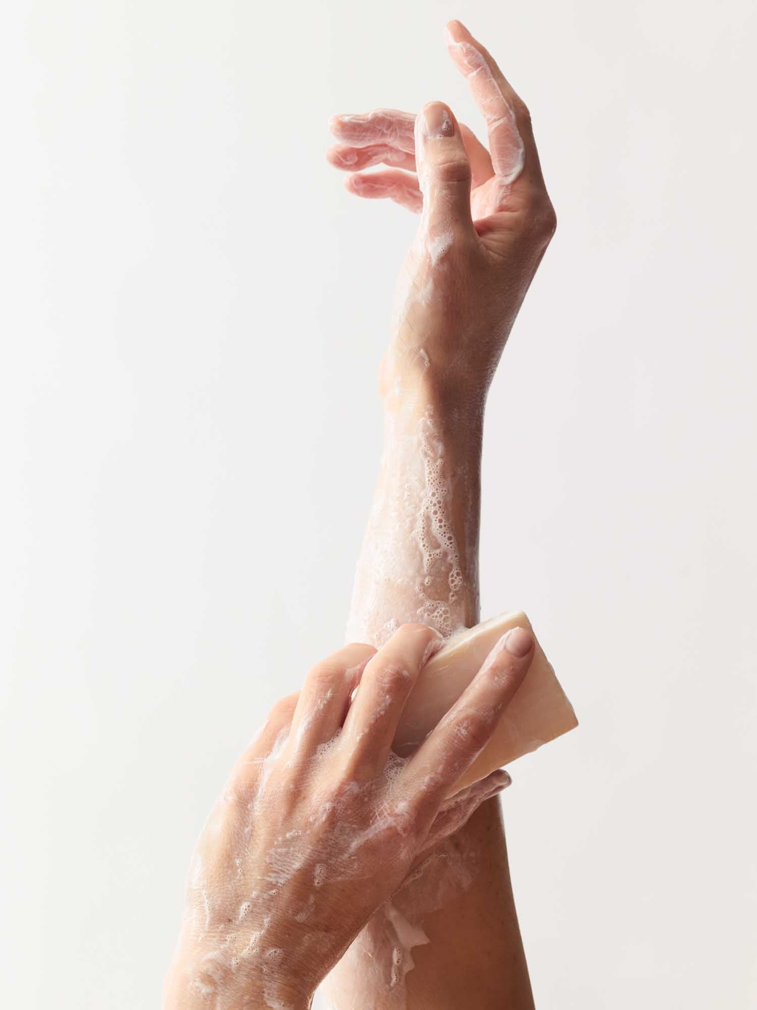 Eine Hand, die die andere Hand mit dem Beruhigenden Reinigungsblock einschäumt