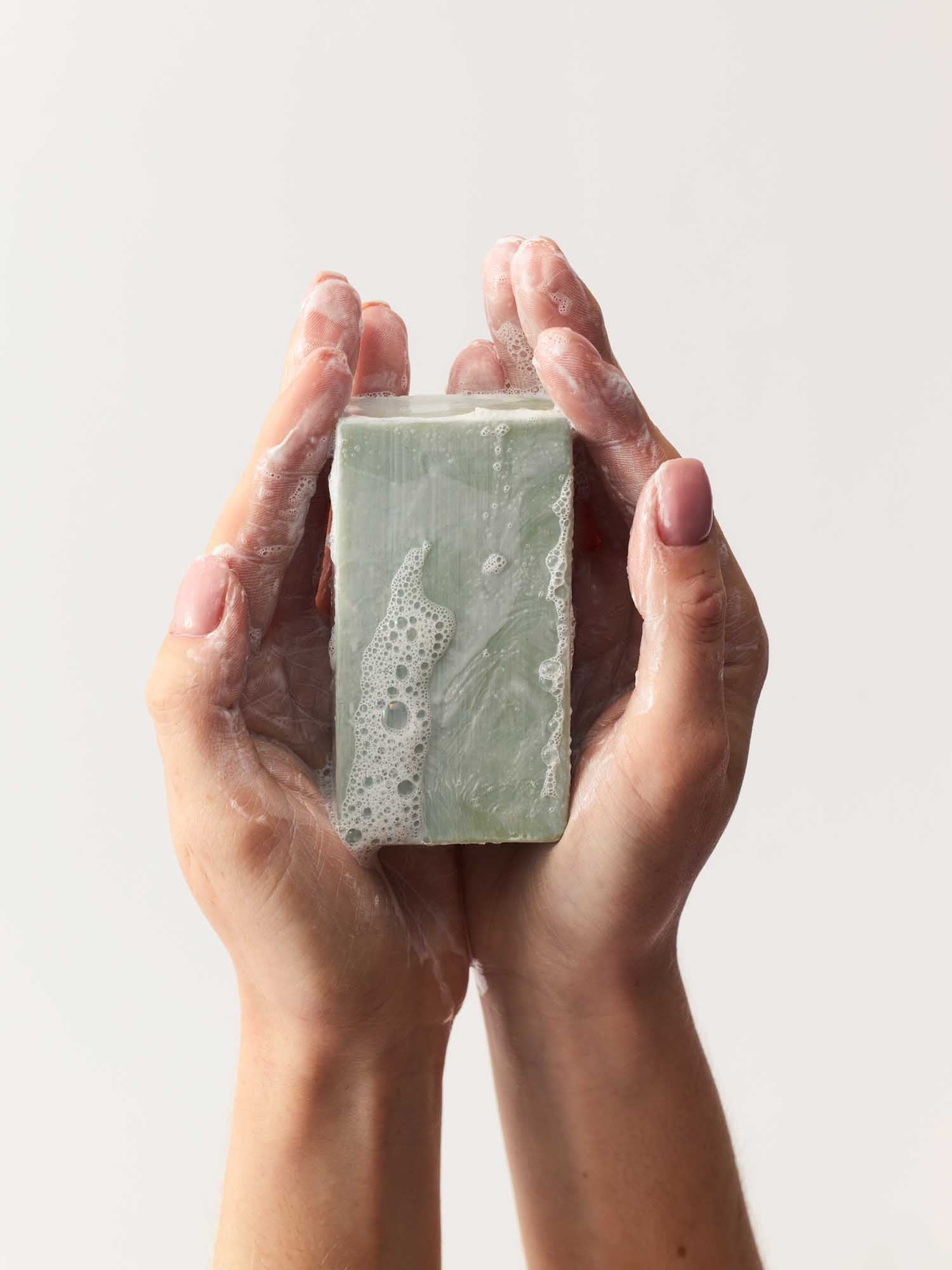 Eine Hand, die den schäumenden Hautklärenden Reinigungsblock hält