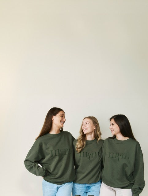 Drei Personen, die sich anschauen und einen nkm Sweater tragen.