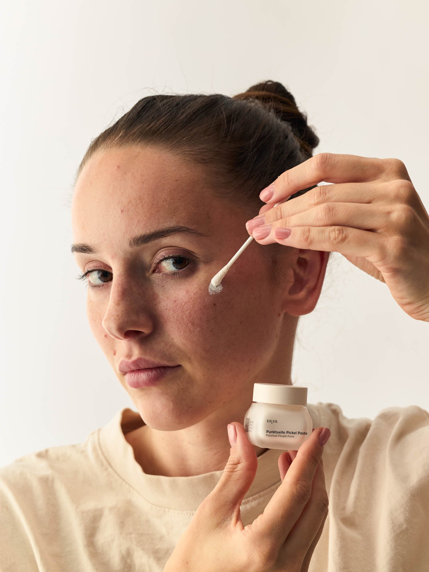 Frau trägt die Punktuelle Pickel Paste von nkm mit einem Wattestäbchen auf
