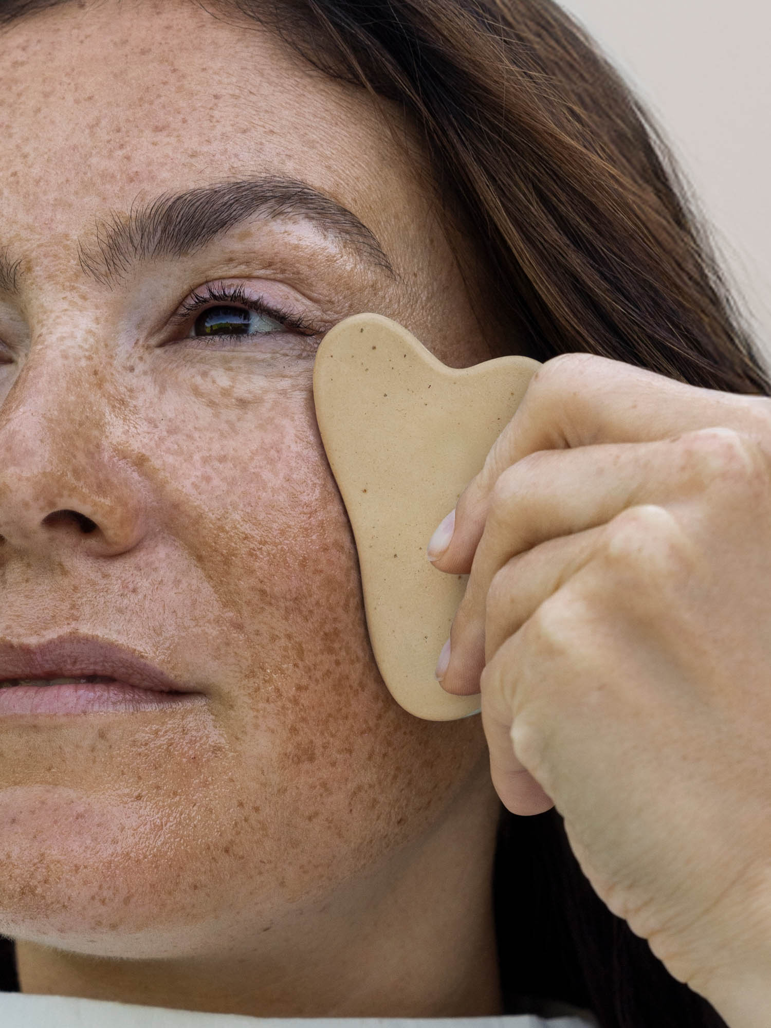 Eine Nahaufnahme von einer Frau, die den Gua Sha anwendet.