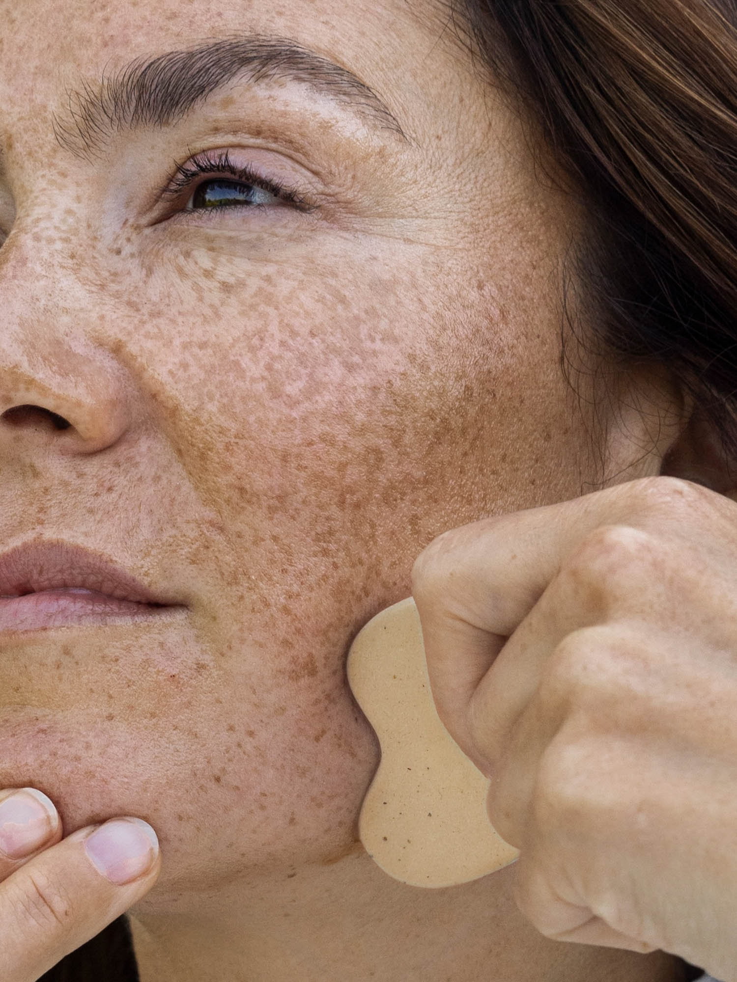 Eine Nahaufnahme von einer Frau, die den Gua Sha anwendet.