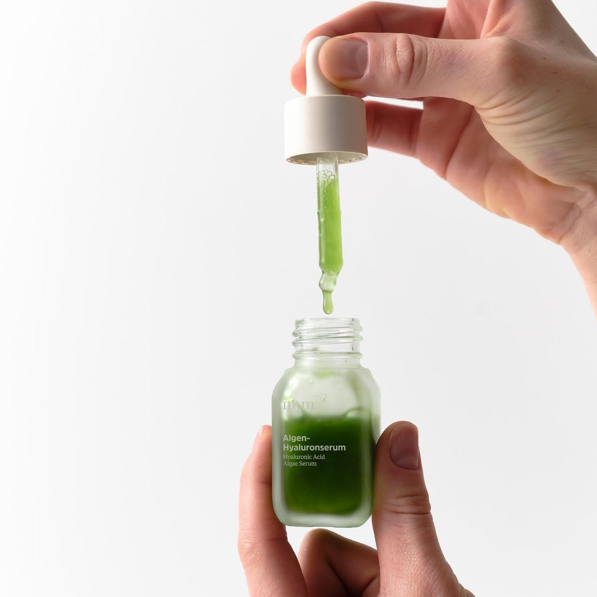 Hand hält Pipette vom Algen-Hyaluronserum von nkm