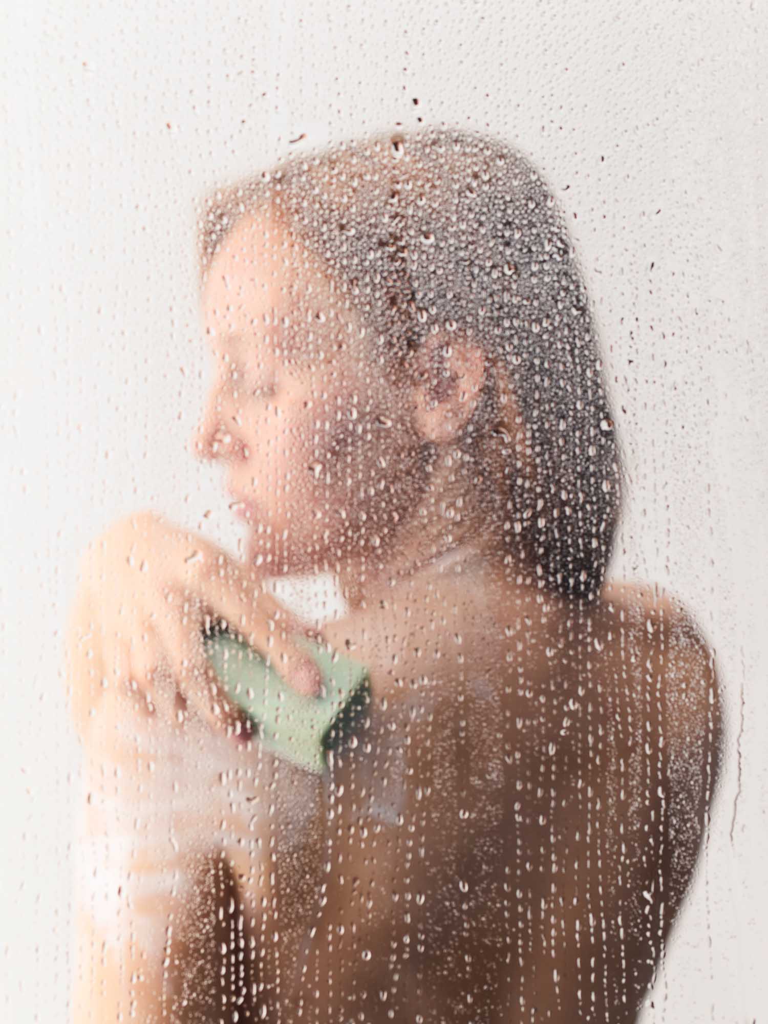 Eine Frau, die in der Dusche sich mit dem Reinigungsblock einschäumt