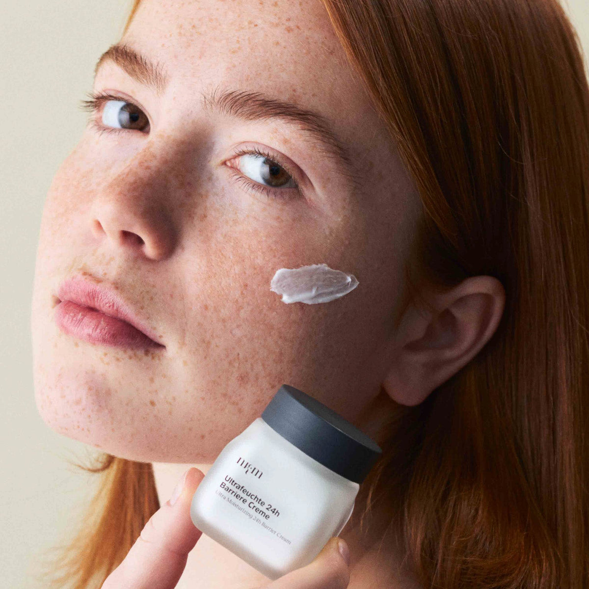 Eine Frau, die die Ultrafeuchte 24h Barriere Creme in der Hand hält