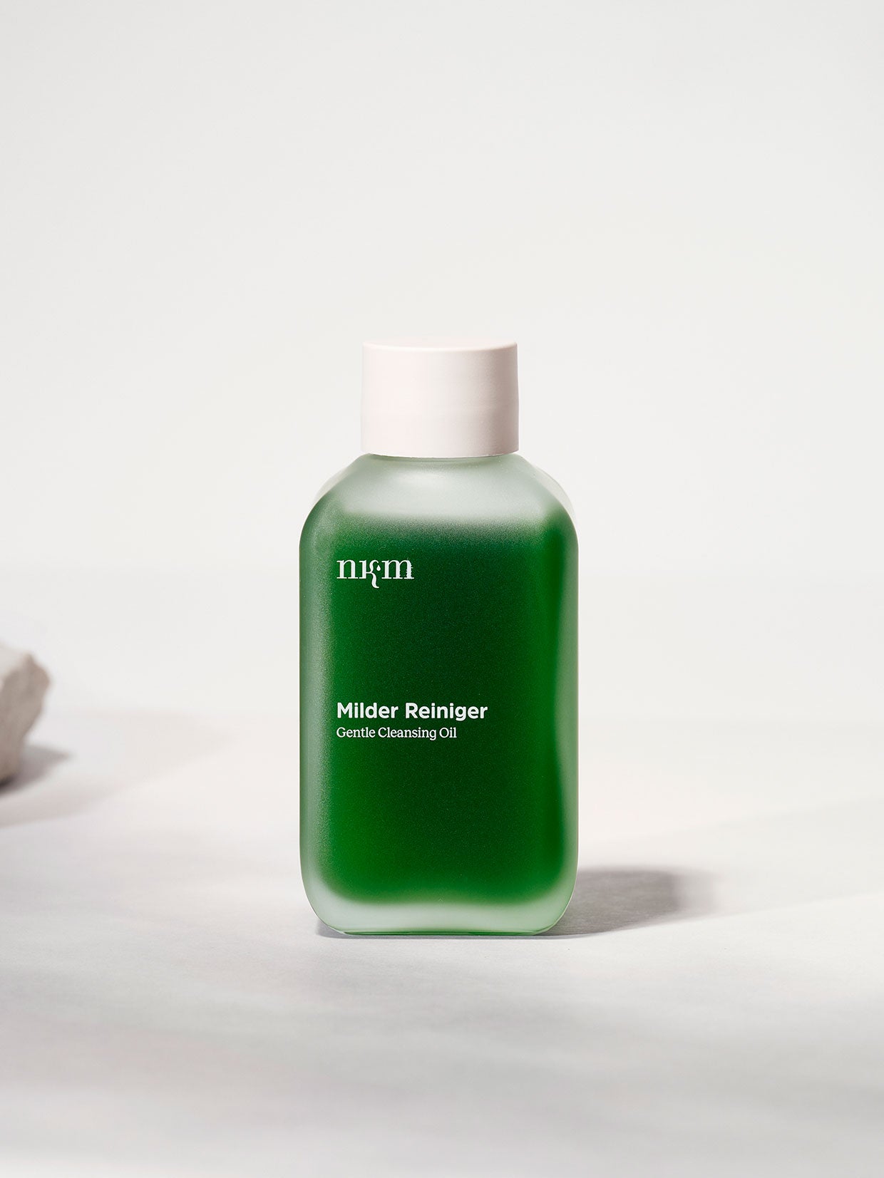 Eine grüne Flasche nkm Naturkosmetik München GmbH Milder Reiniger mit weißer Kappe ruht auf einer weißen Fläche, ideal für unreine Haut und angereichert mit Brokkolisamenöl.