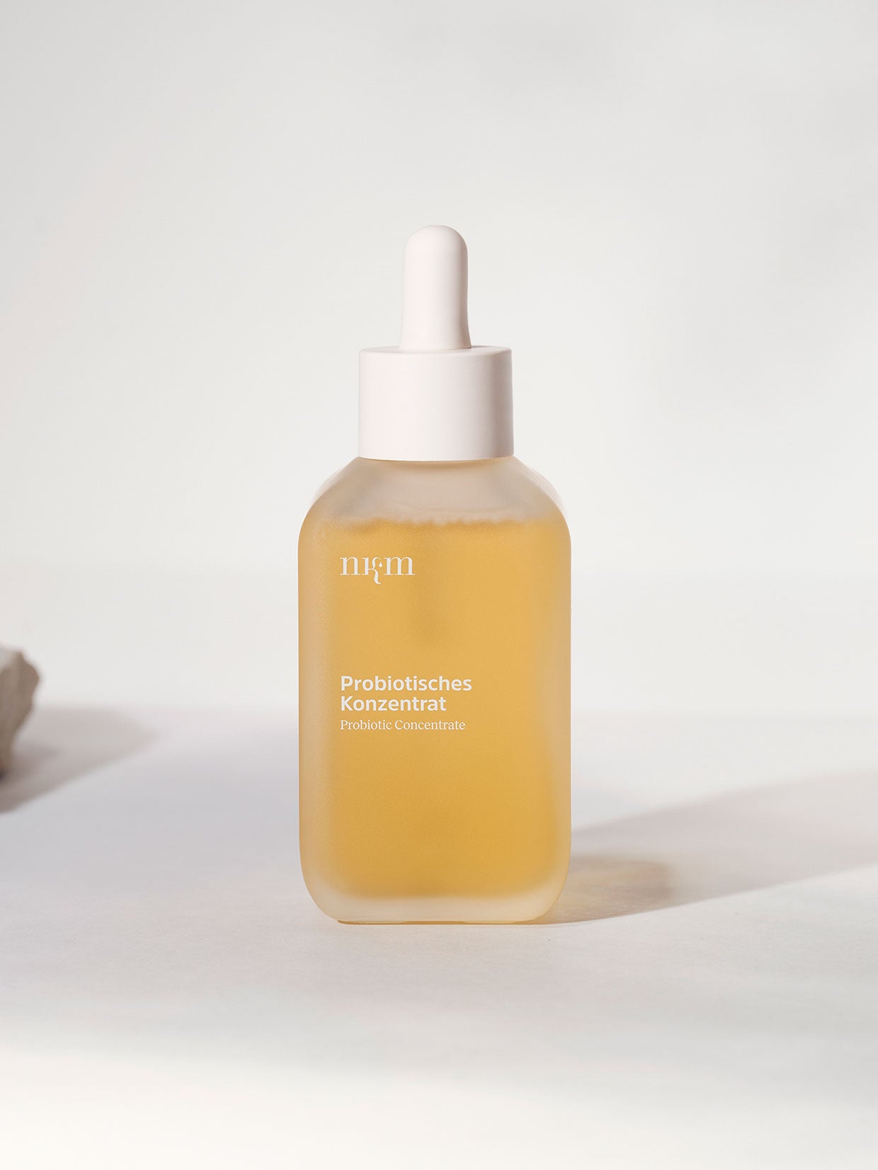 In einer gläsernen Tropfflasche der nkm Naturkosmetik München GmbH mit der Aufschrift Probiotisches Konzentrat befindet sich ein hellgelbes, feuchtigkeitsspendendes Konzentrat zur Unterstützung der Hautbarriere.