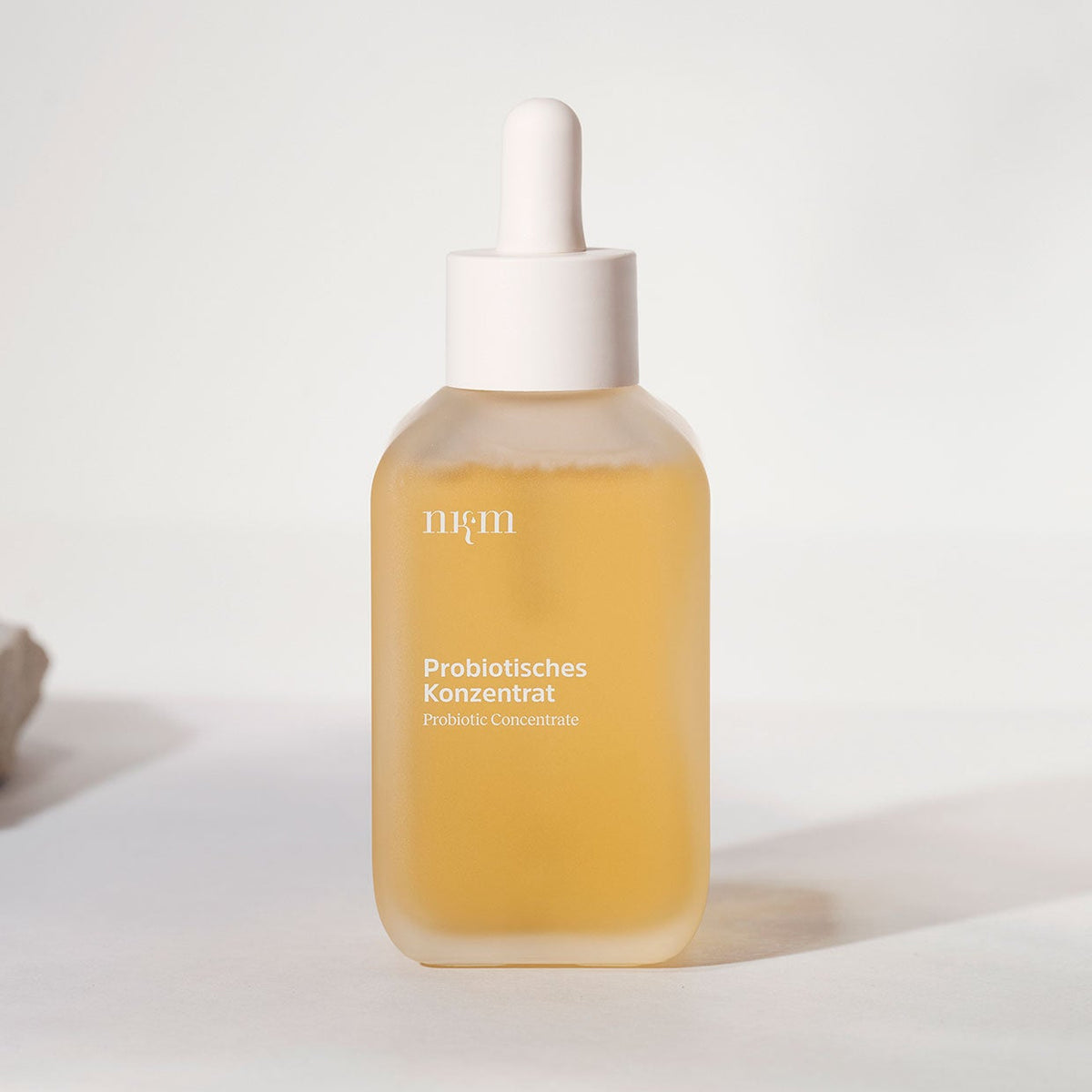 In einer gläsernen Tropfflasche der nkm Naturkosmetik München GmbH mit der Aufschrift Probiotisches Konzentrat befindet sich ein hellgelbes, feuchtigkeitsspendendes Konzentrat zur Unterstützung der Hautbarriere.
