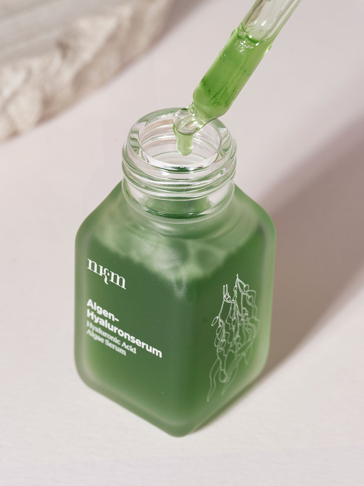 Das Algen-Hyaluronserum Duo der nkm Naturkosmetik München GmbH kommt in einer grünen Tropfflasche mit Glaspipette und enthält ein mit Seetang und Hyaluron angereichertes Serum für eine verbesserte Hautelastizität.