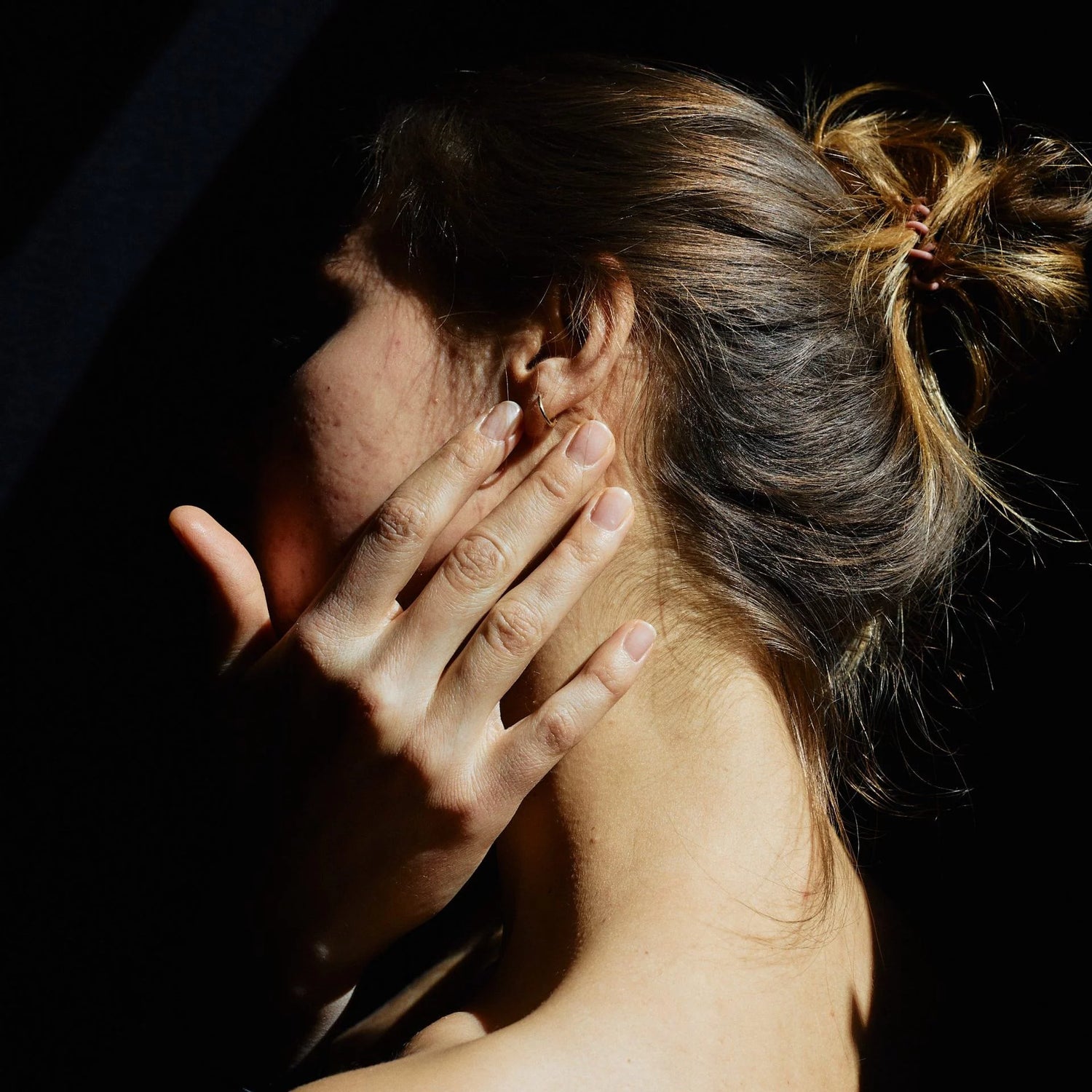 Frau mit Hand im Gesicht im Halbdunklem