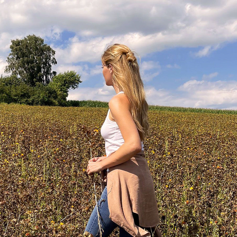 Frau auf einem Feld mit blauem Himmel und Wolken