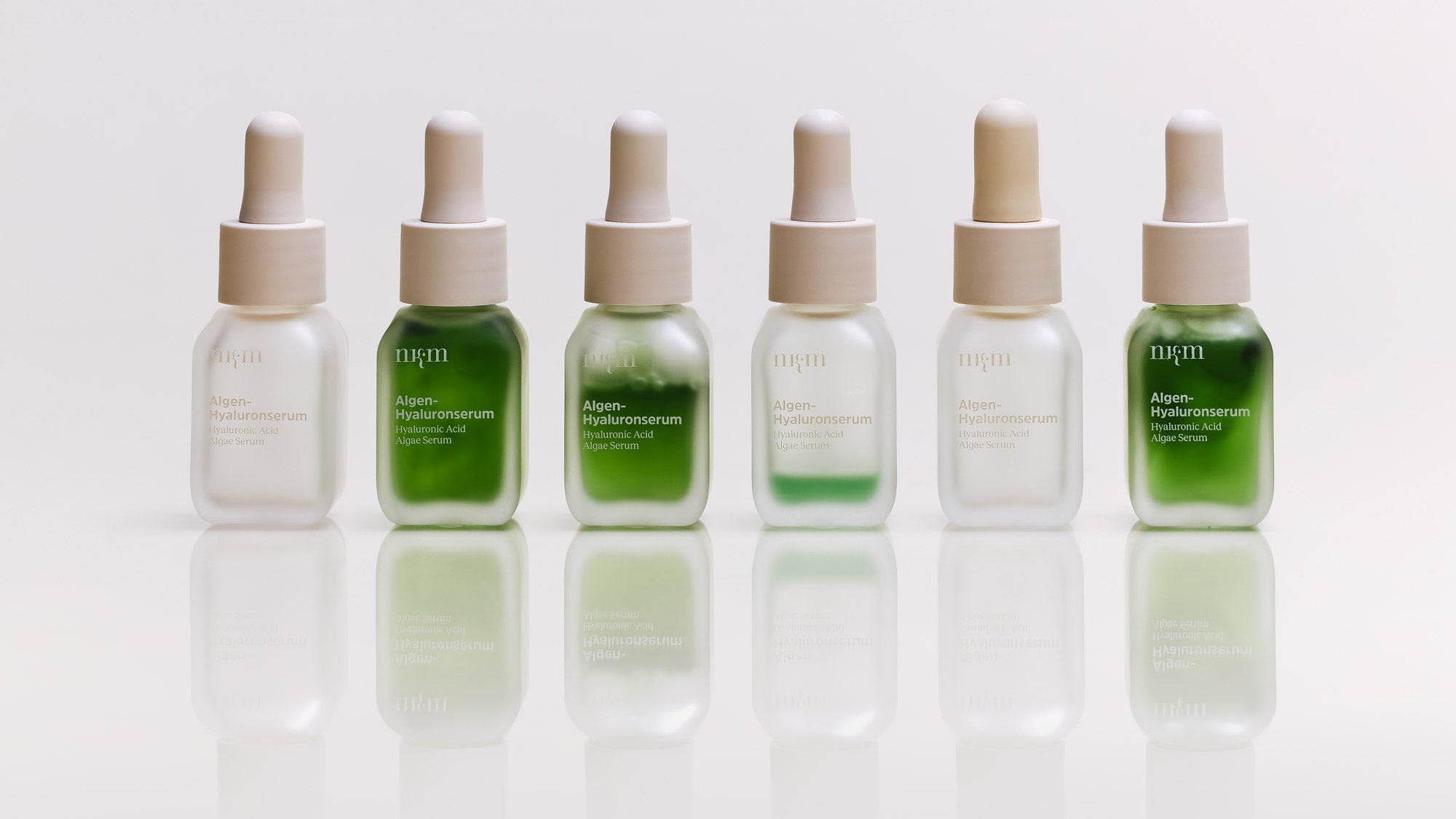 Sechs Algen-Hyaluronserumflaschen nebeneinander stehend, teilweise leer