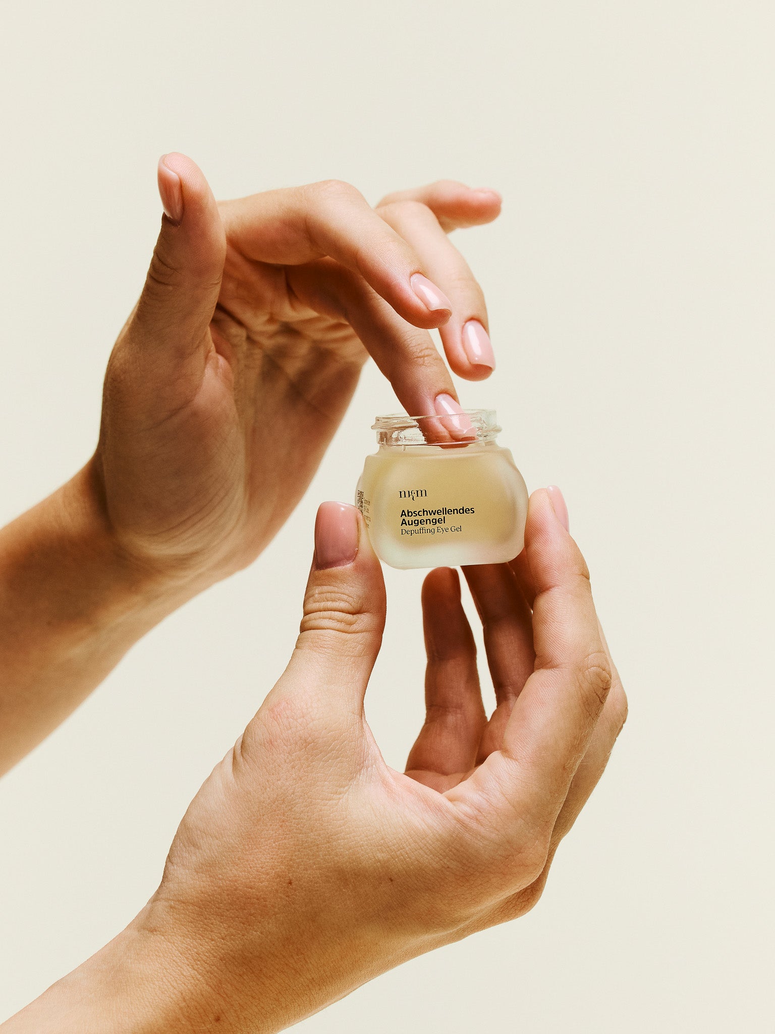 Hand hält Abschwellendes Augengel und nimmt Produkt mit Finger auf