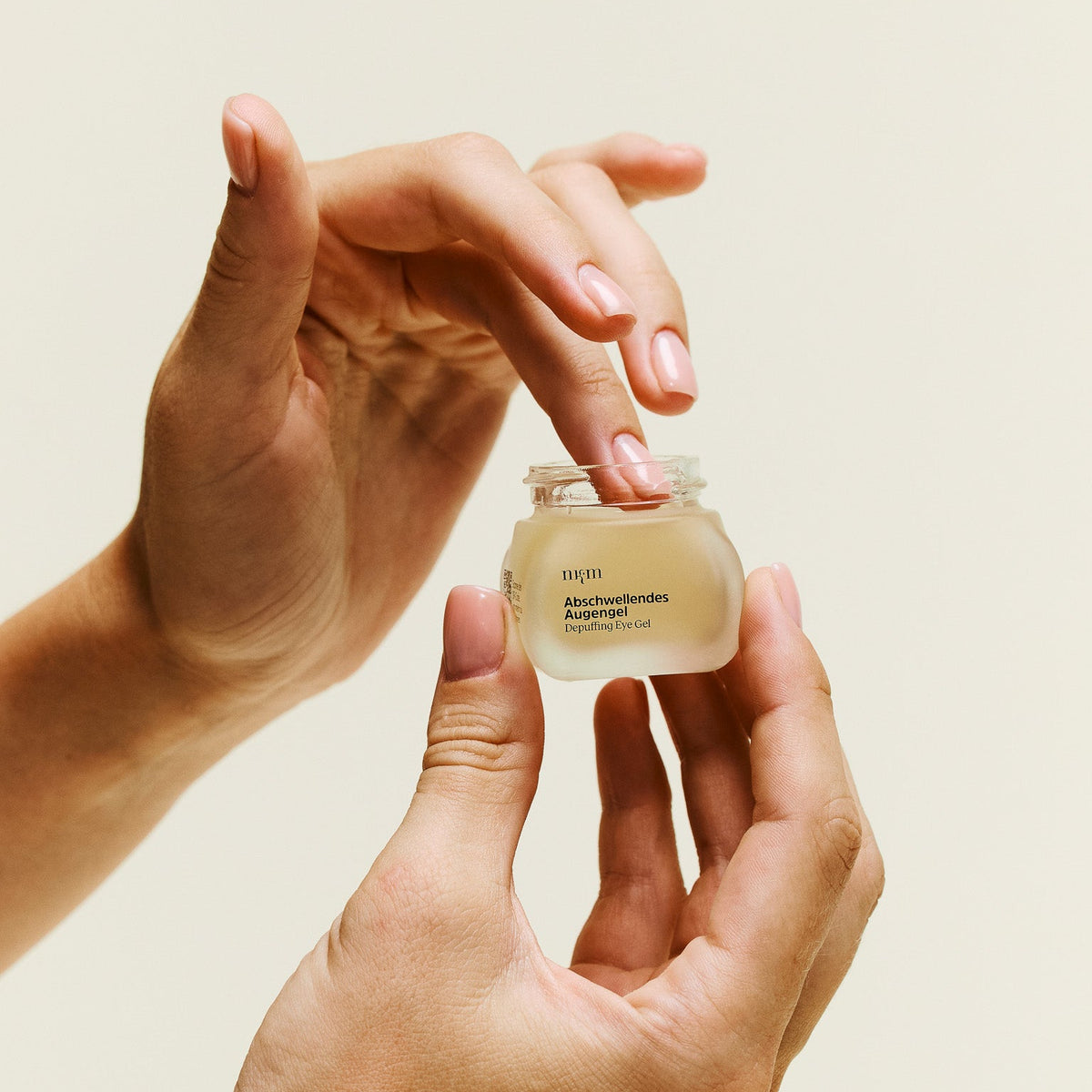 Hand hält Abschwellendes Augengel und nimmt Produkt mit Finger auf