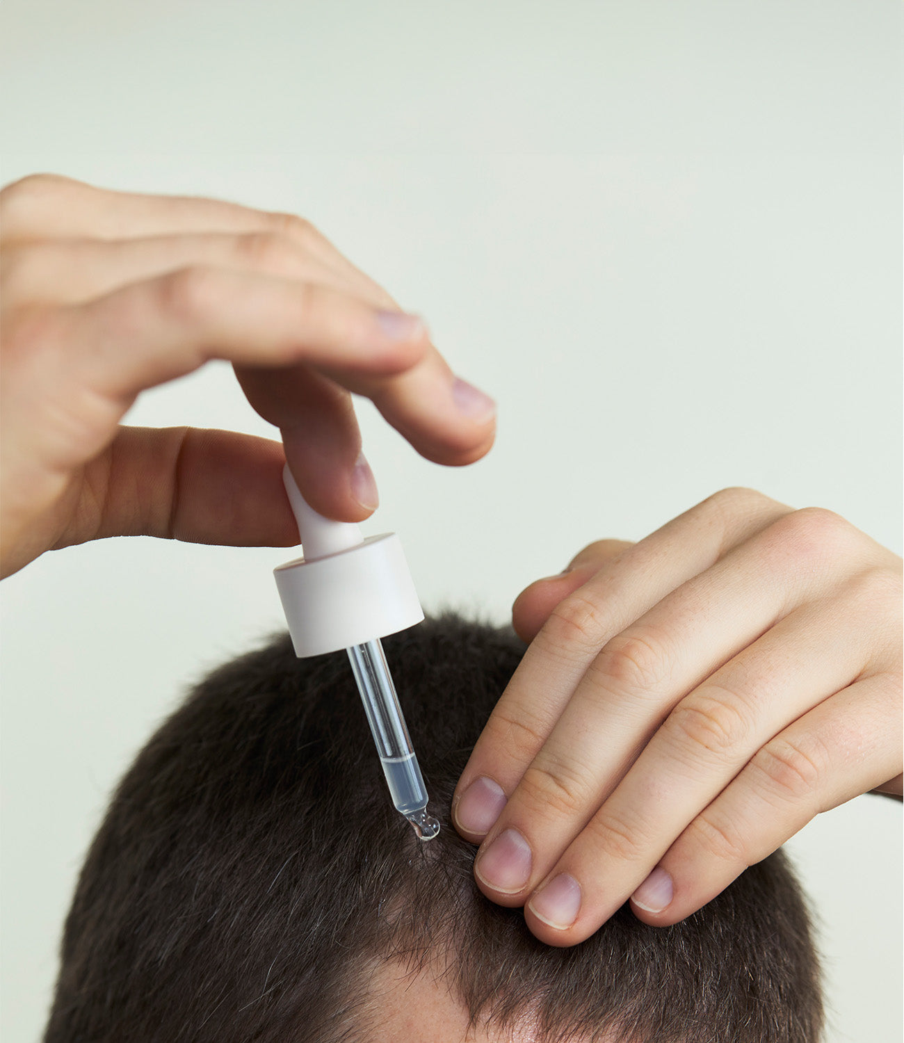 Ein Mann, der ein Kopfhaut Serum von nkm nutzt