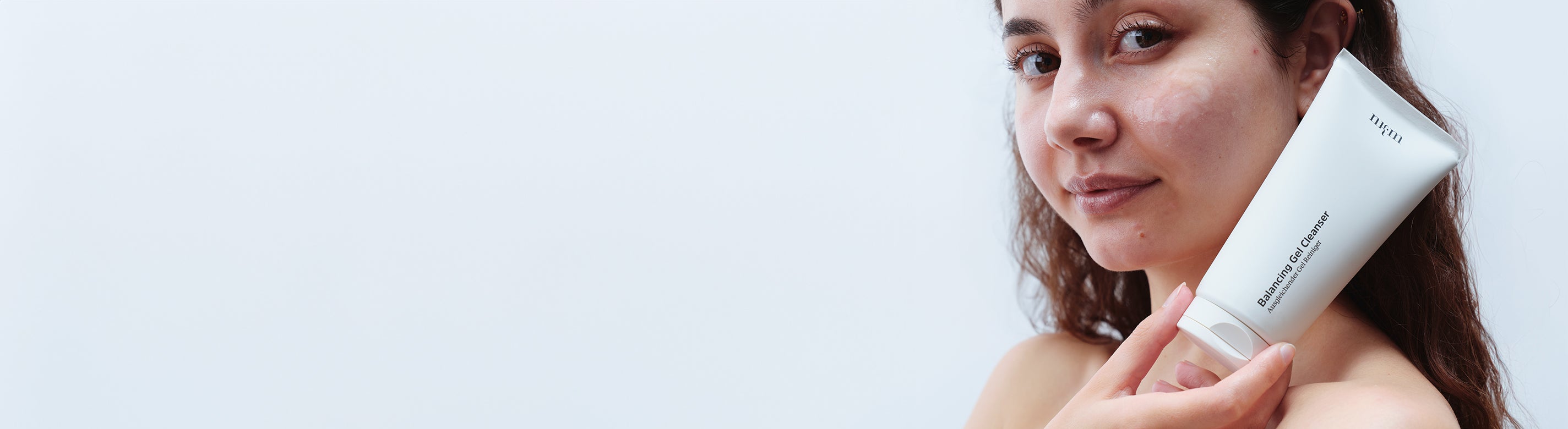 Frau mit dunklen Haaren hält Balancing Gel Cleanser in der Hand