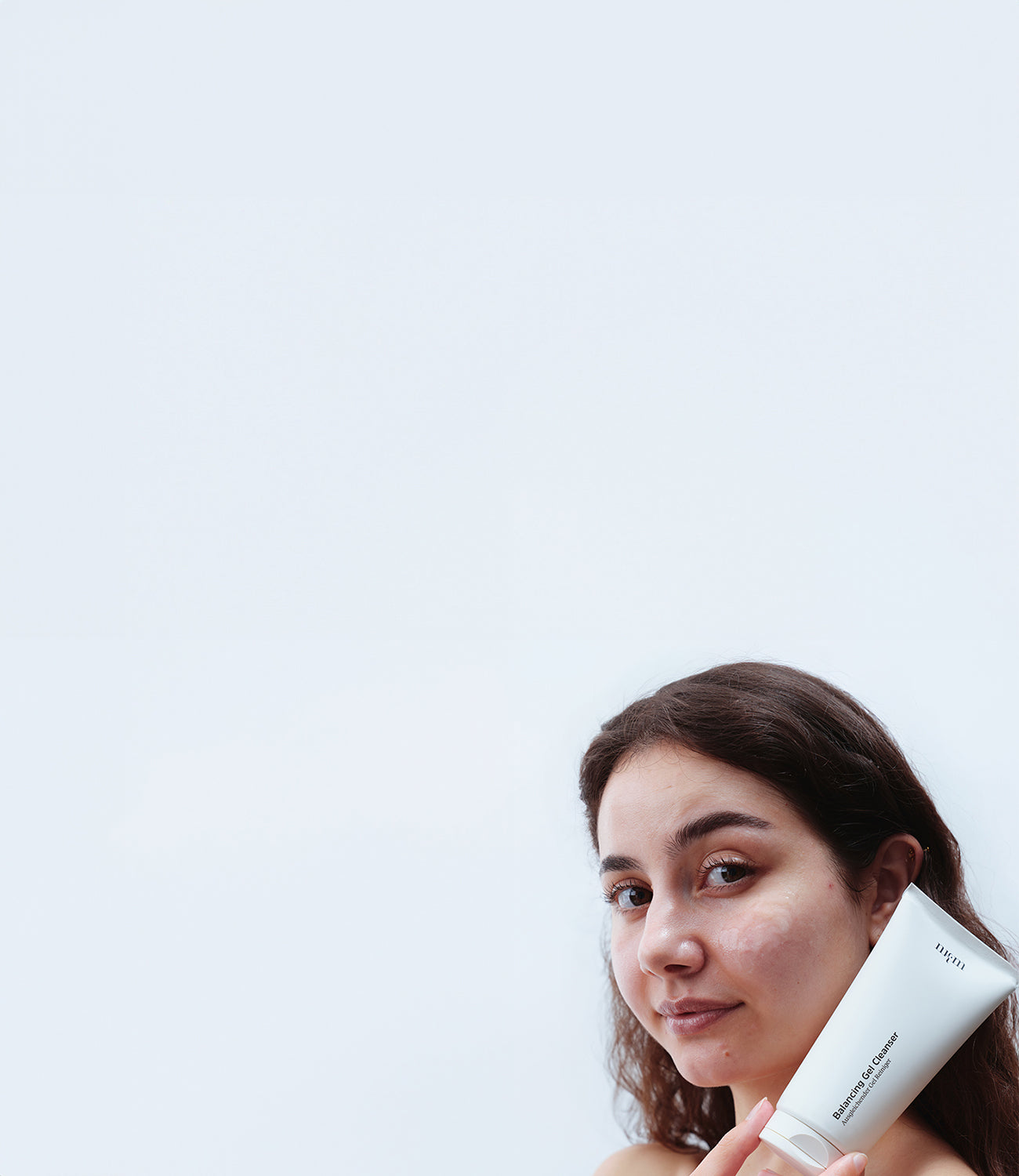 Frau mit dunklen Haaren hält Balancing Gel Cleanser in der Hand