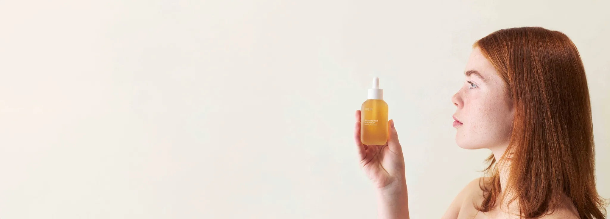 Eine Frau mit sensibler Haut, die ein nkm Produkt in der Hand hält.