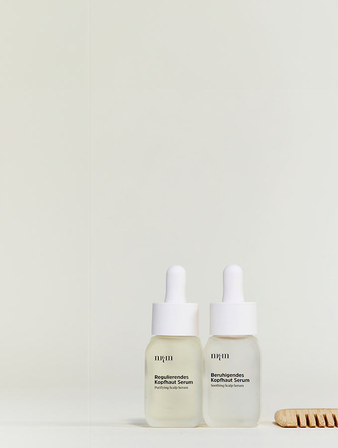 Das Beruhigende und Regulierende Kopfhautserum von nkm, daneben ein Holzkamm