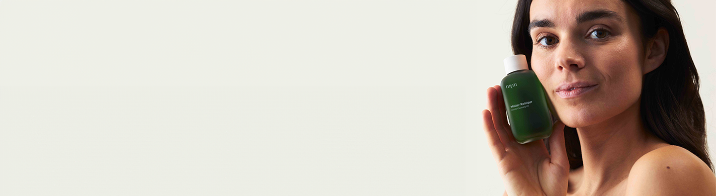 Frau mit dunklen Haaren, die den Milden Reiniger in der Hand hält