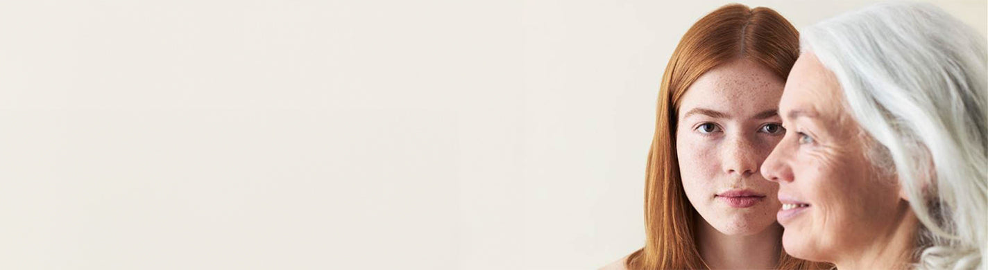 Eine Frau mit grauen Haaren schaut nach links, hinter ihr eine Frau mit roten Haaren schaut geradeaus
