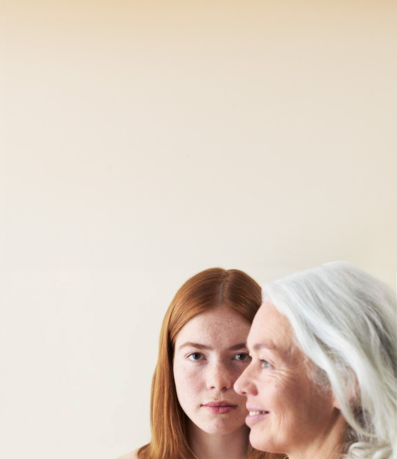 Eine Frau mit grauen Haaren schaut nach links, hinter ihr eine Frau mit roten Haaren schaut geradeaus