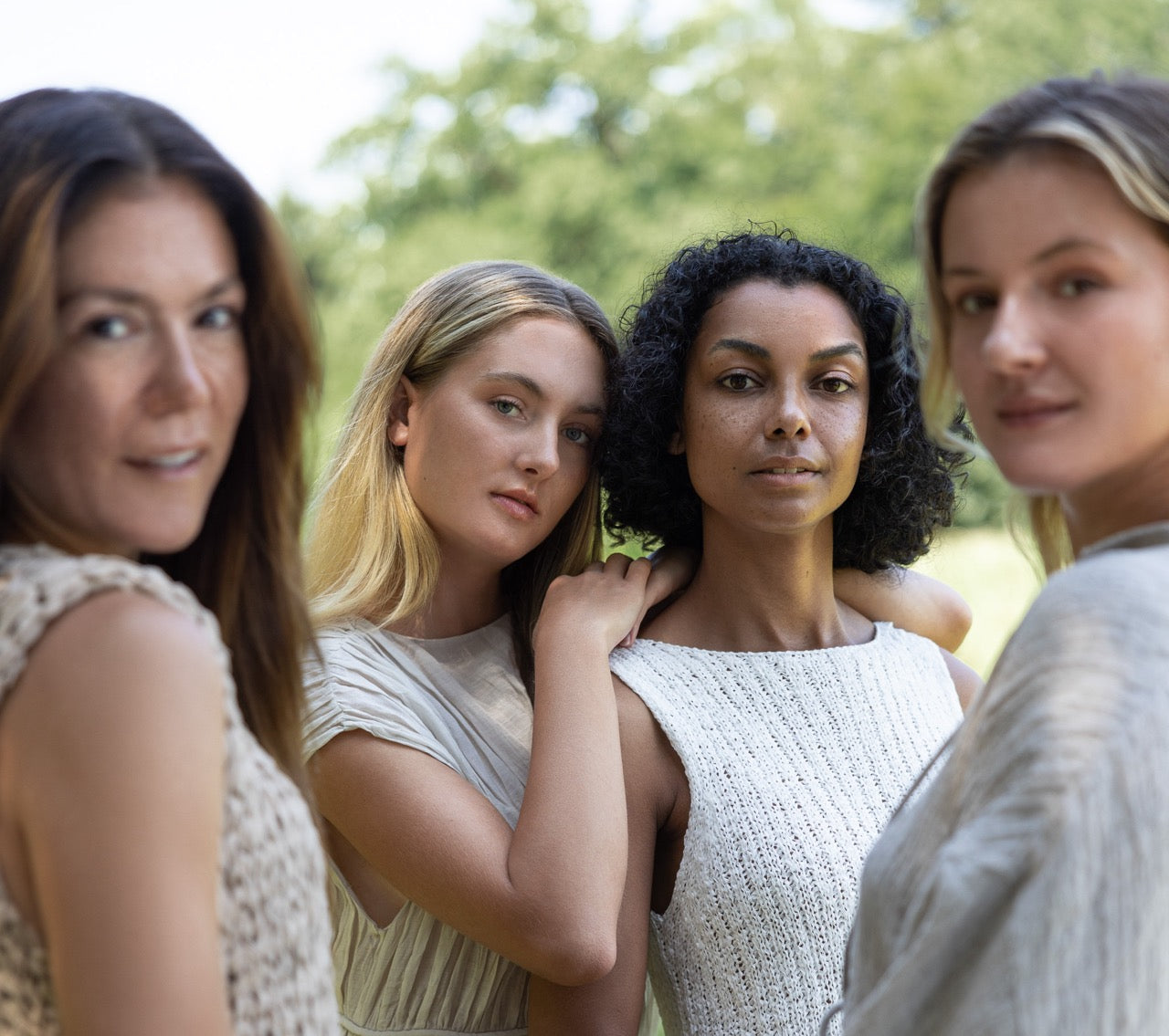 vier Models in der Natur in beiger Kleidung