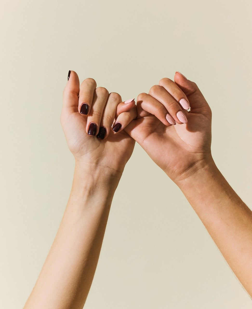 Zwei Hände, die sich mit dem kleinen Finger halten vor neutralem Hintergrund