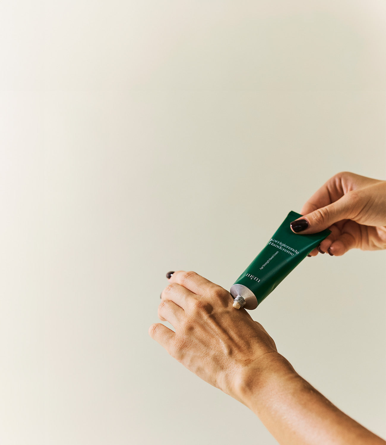 Zwei Hände die links in das Bild kommen, die eine Hand hält die Korrigierende Handcreme in der Hand