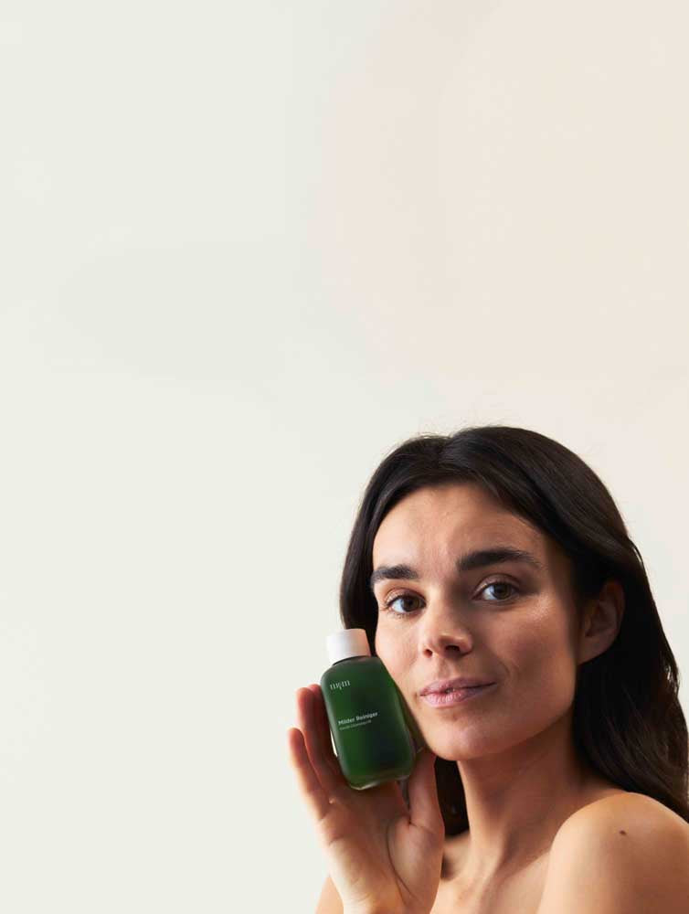 Frau mit dunklen Haaren, die den Milden Reiniger in der Hand hält