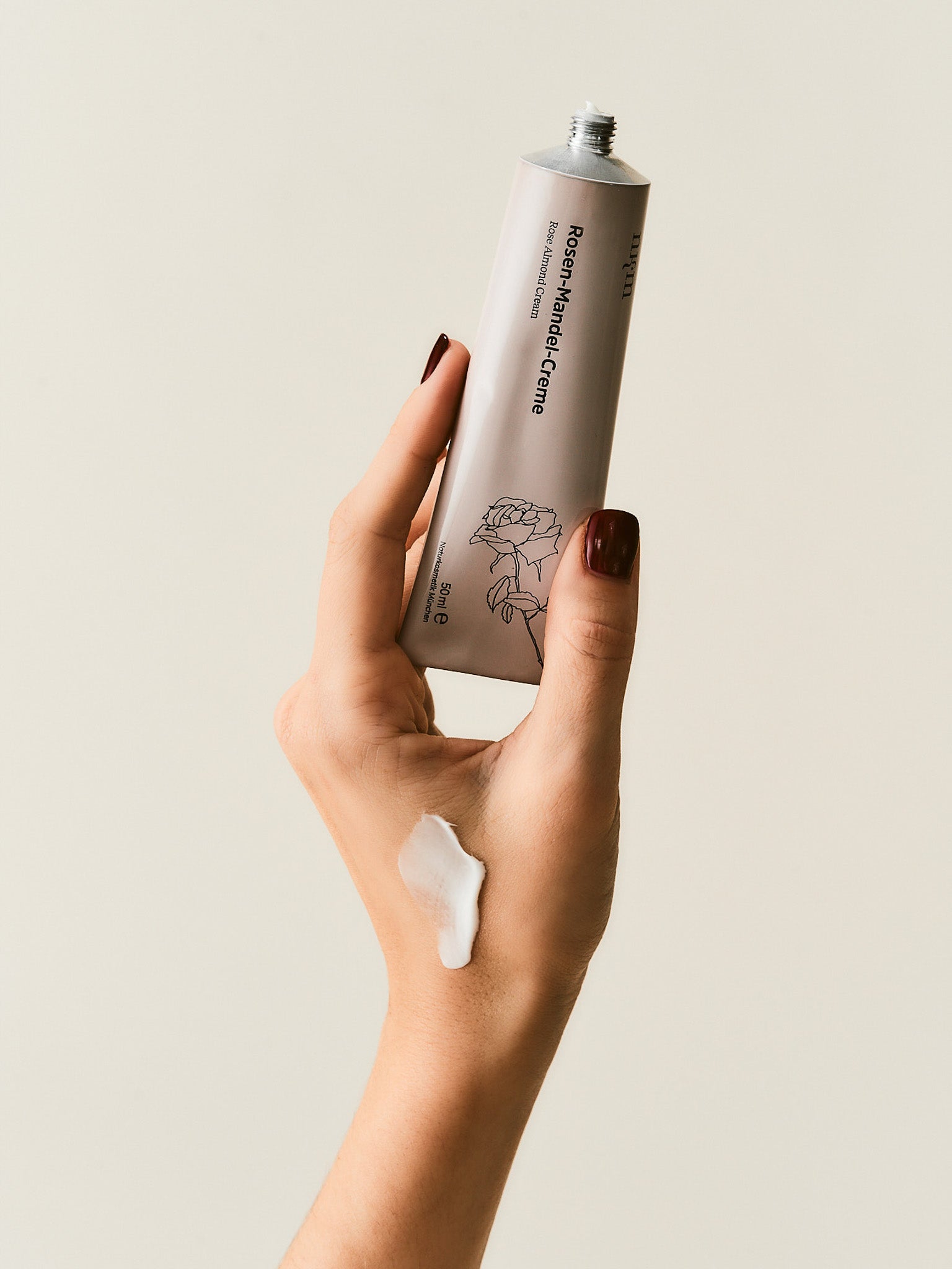 Hand hält Rosen-Mandel-Creme