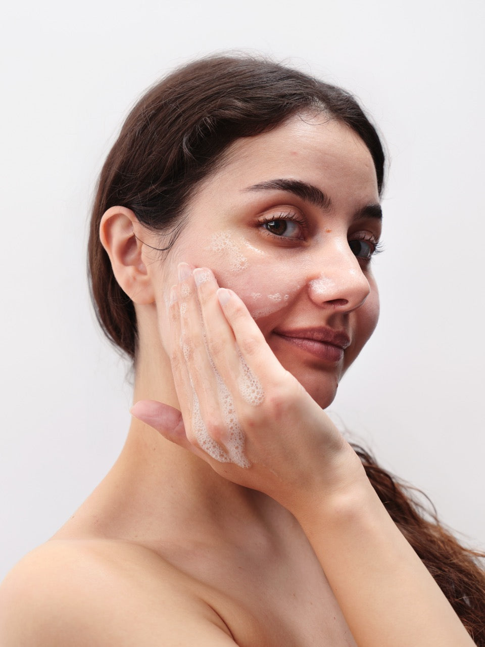 Frau mit dunklen Haaren trägt Gesichtsreinigung auf