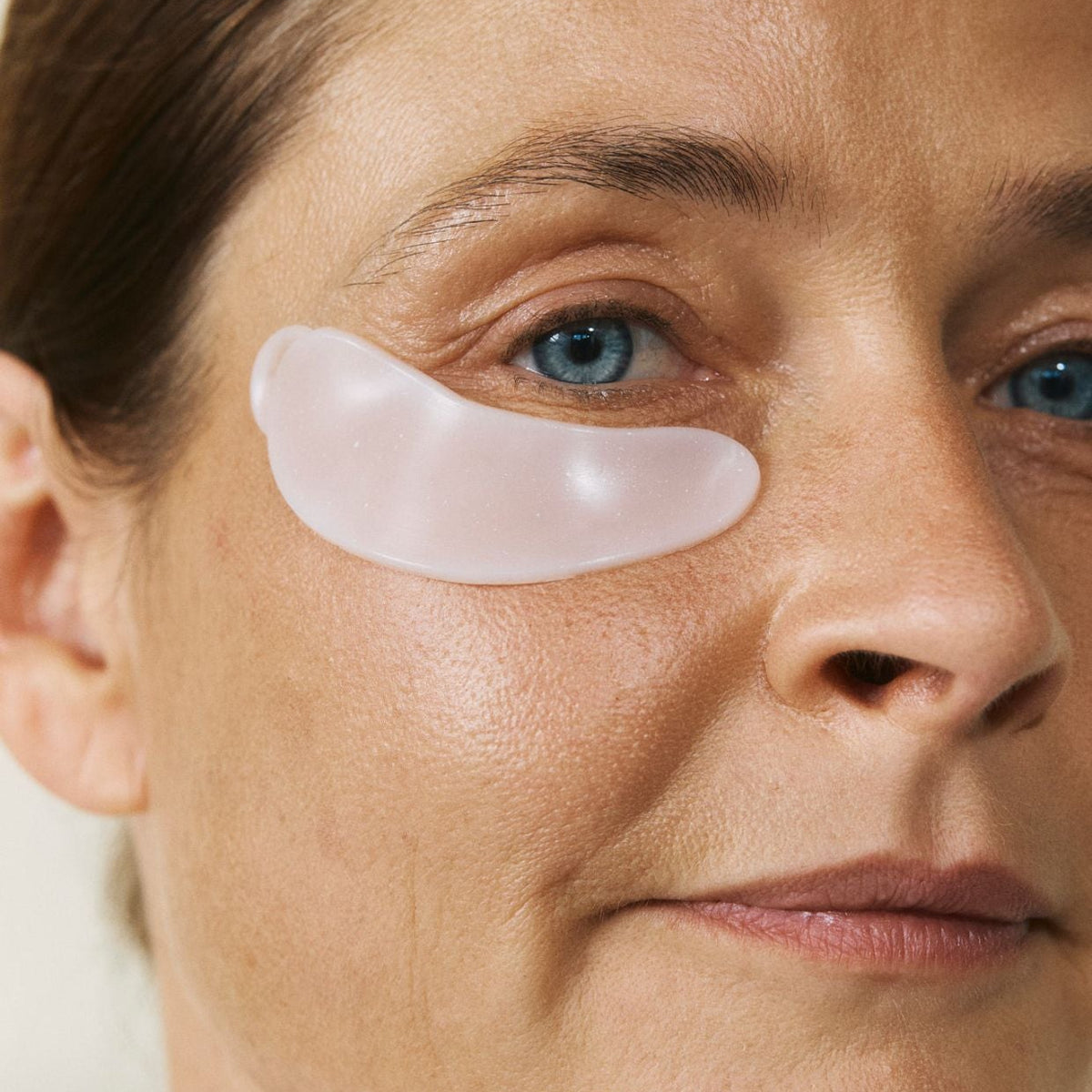 Eine Frau mit reifer Haut trägt die wiederverwendbaren nkm Augenpads