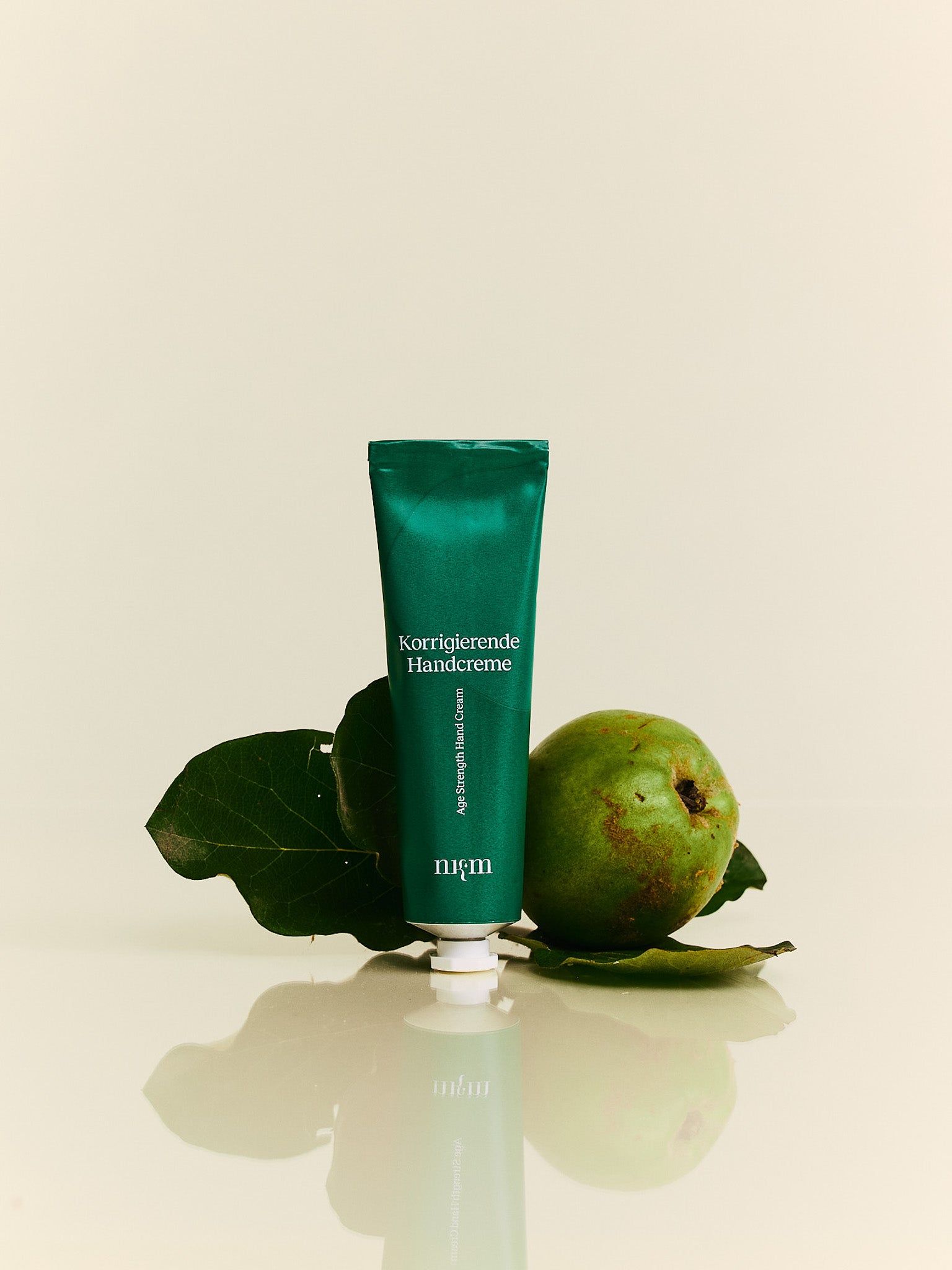 Korriegierende Handcreme von nkm neben einer Quitte