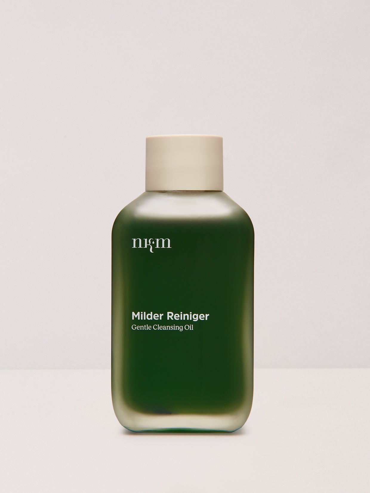 Eine grüne Flasche nkm Naturkosmetik München GmbH Milder Reiniger Gentle Cleansing Oil mit Brokkolisamenöl und einer beigen Kappe, ideal für unreine Haut, dargestellt auf weißem Hintergrund.