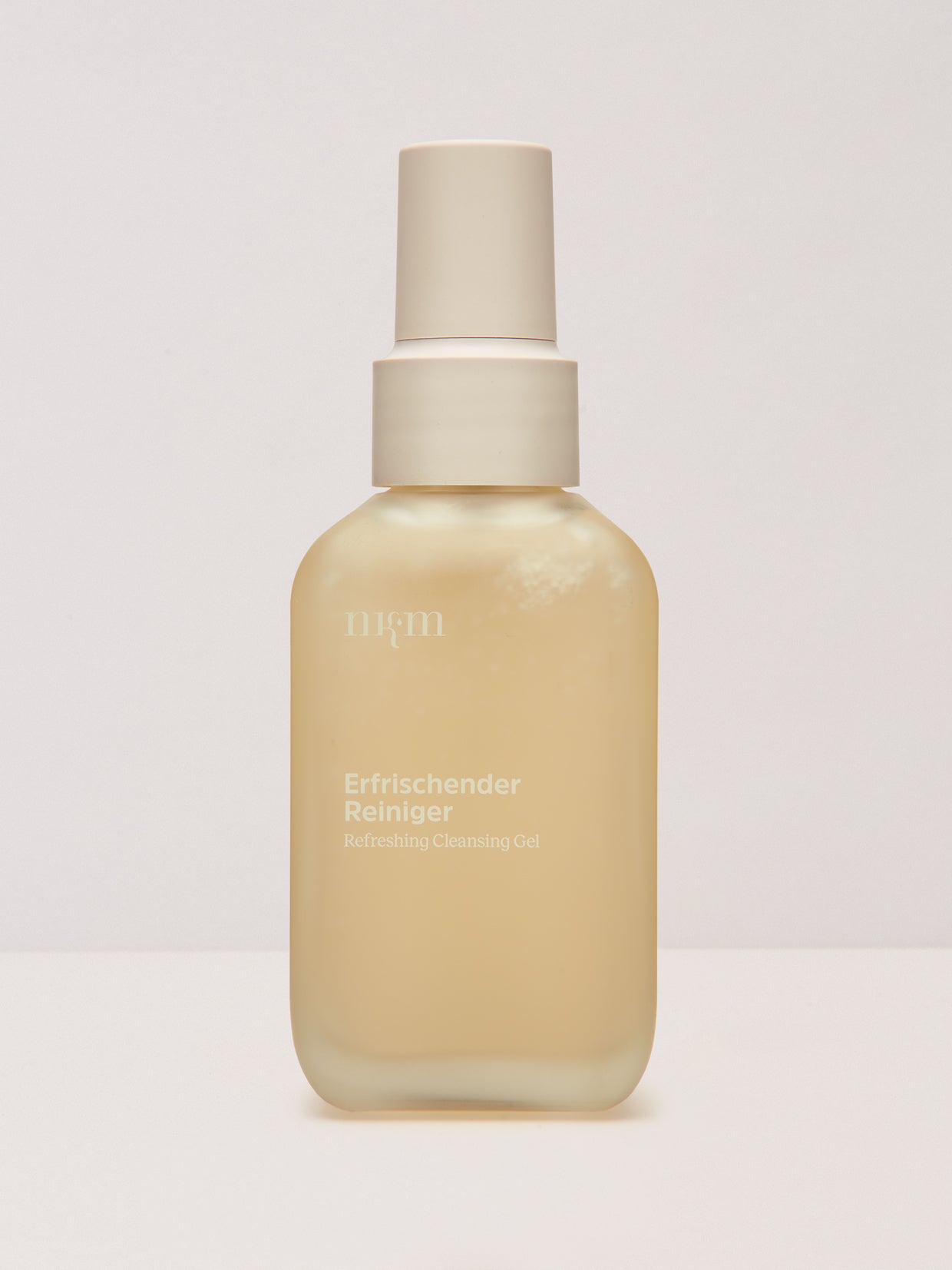 Eine gefrostete Flasche des Erfrischender Reinigers der nkm Naturkosmetik München GmbH steht auf einem schlichten Hintergrund.