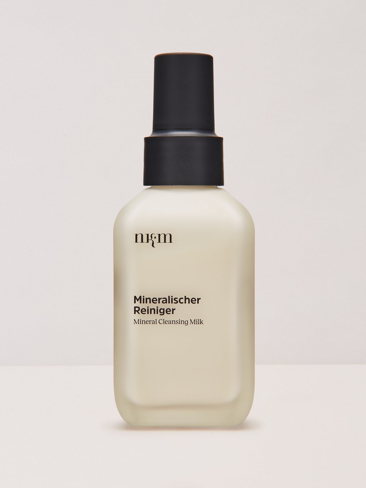 Ein beiger Flakon von nkm Naturkosmetik München GmbH Mineralischer Reiniger mit einer schwarzen Pumpe, ideal für sensible Haut und angereichert mit entzündungshemmendem Zink.