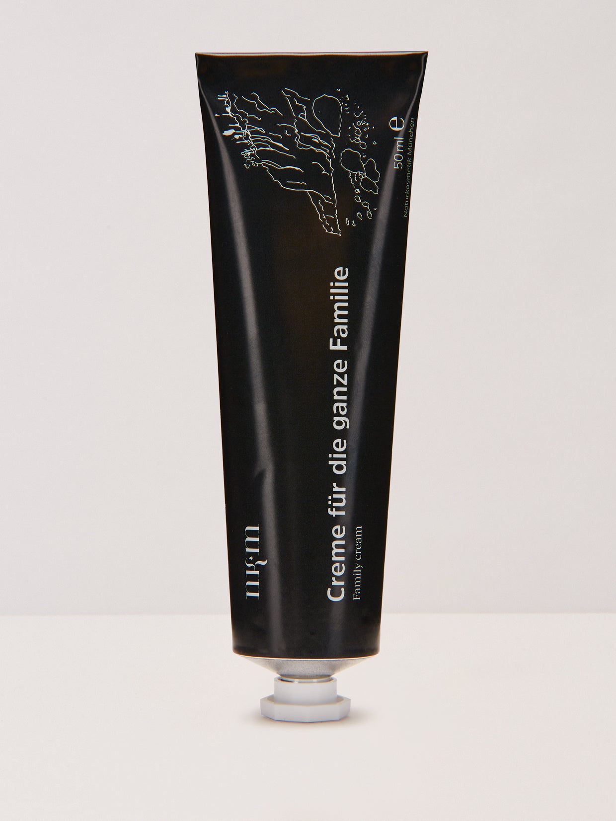 Eine schwarze Tube der Creme für die ganze Familie der nkm Naturkosmetik München GmbH steht aufrecht auf einer weißen Fläche - ideal für die intensive Pflege der empfindlichen Babyhaut.