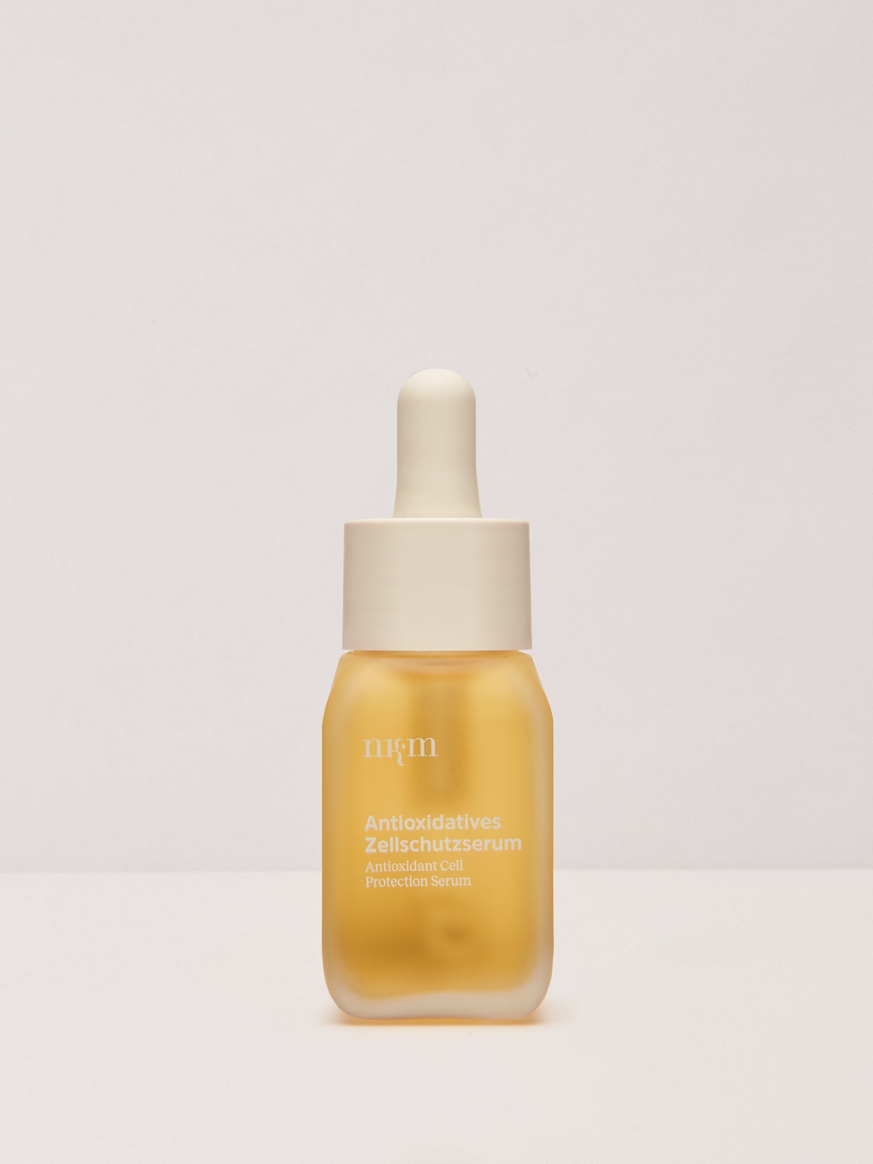 Ein gelbes Serumfläschchen mit weißem Tropfverschluss, beschriftet mit "Antioxidatives Zellschutzserum" von nkm Naturkosmetik München GmbH, mit Antioxidantien wie Resveratrol.