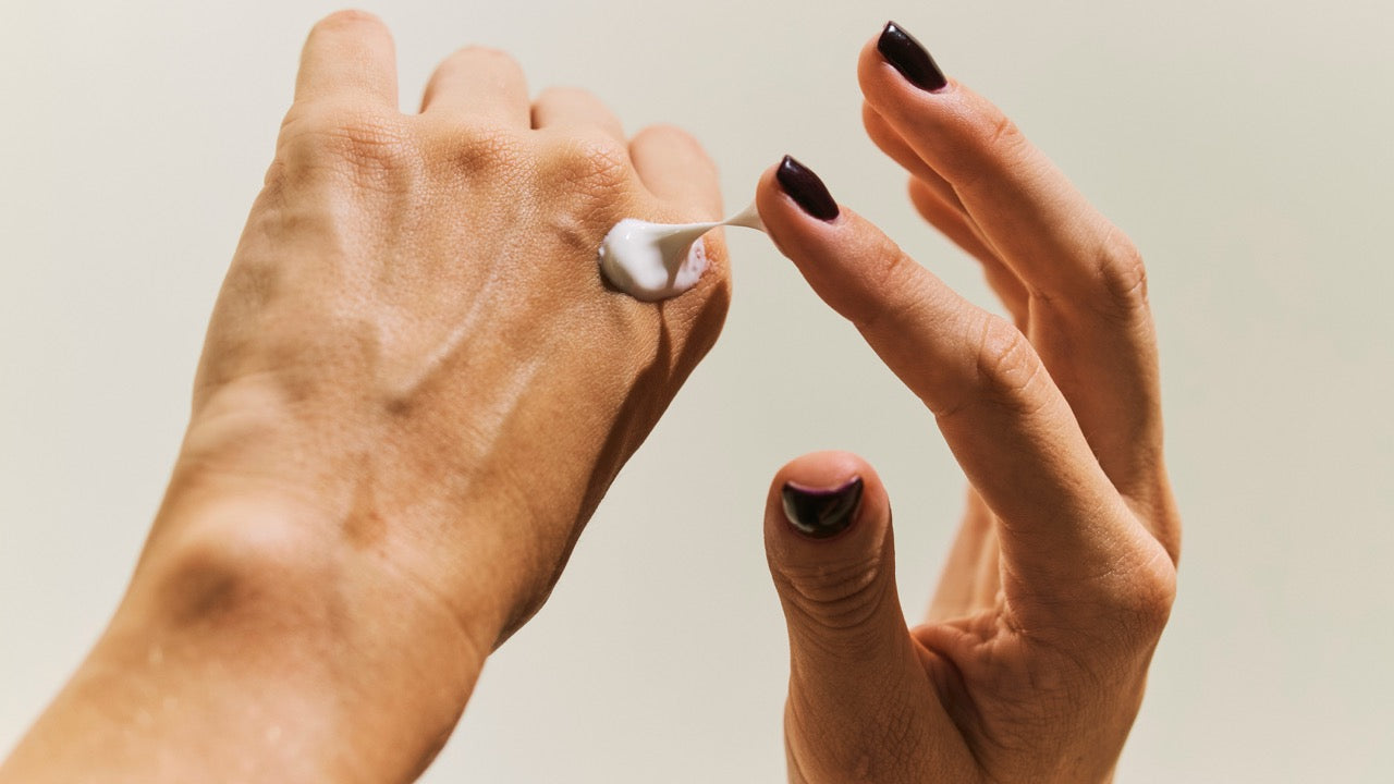 Zwei Hände tragen Handcreme auf