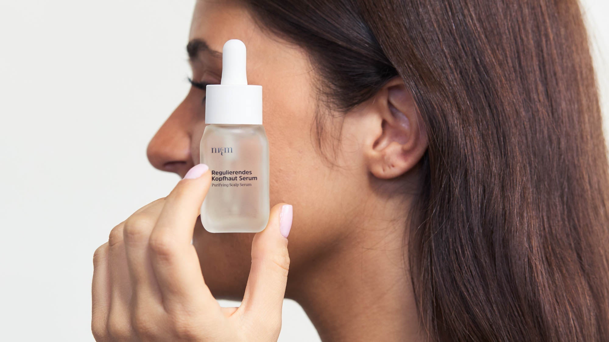 Eine Frau, die das Beruhigende Kopfhaut Serum in der Hand hält