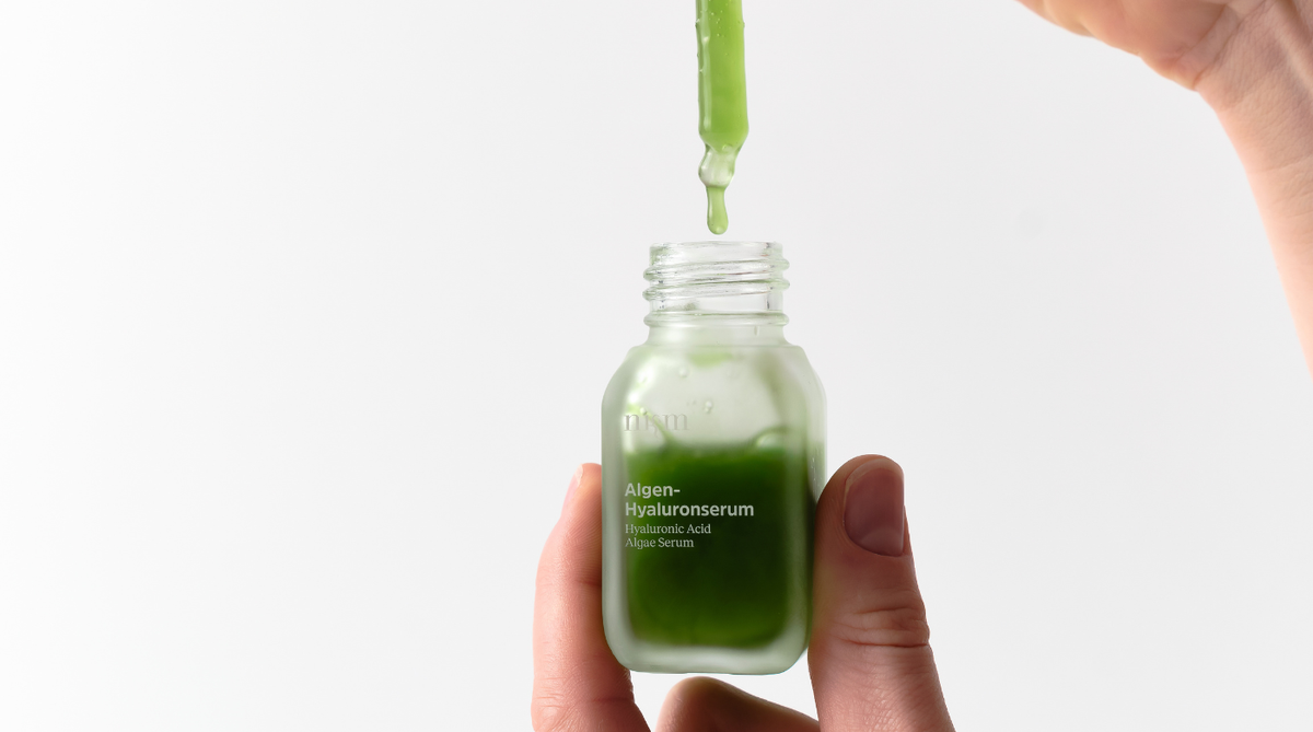 Hand hält Algen-Hyaluronserum von nkm.