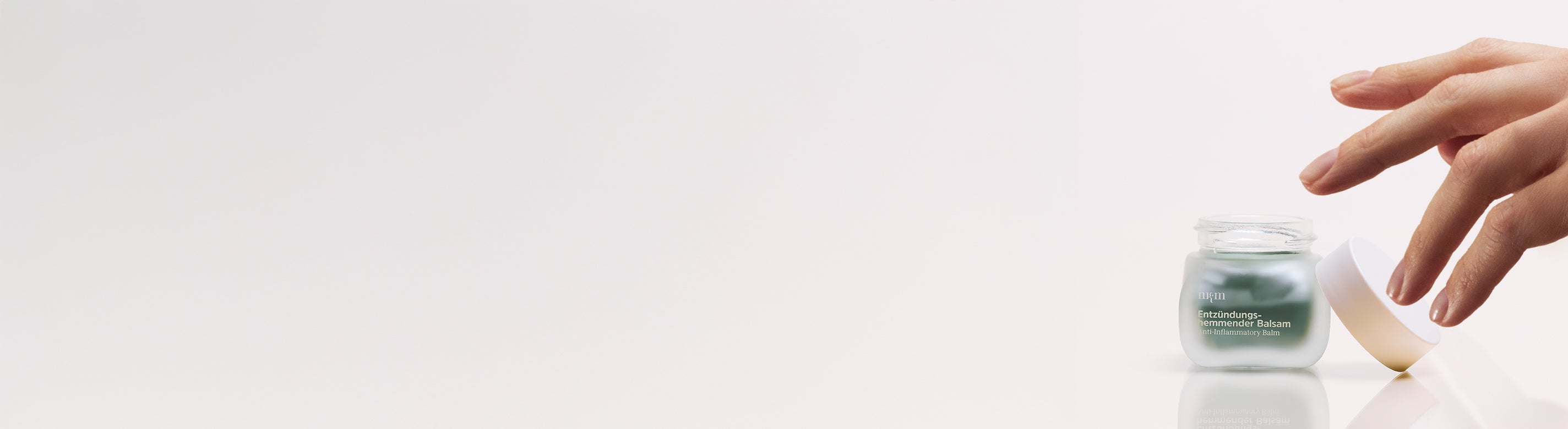 Entzündungshemmender Balsam und eine Hand, die nach dem Tiegel greift